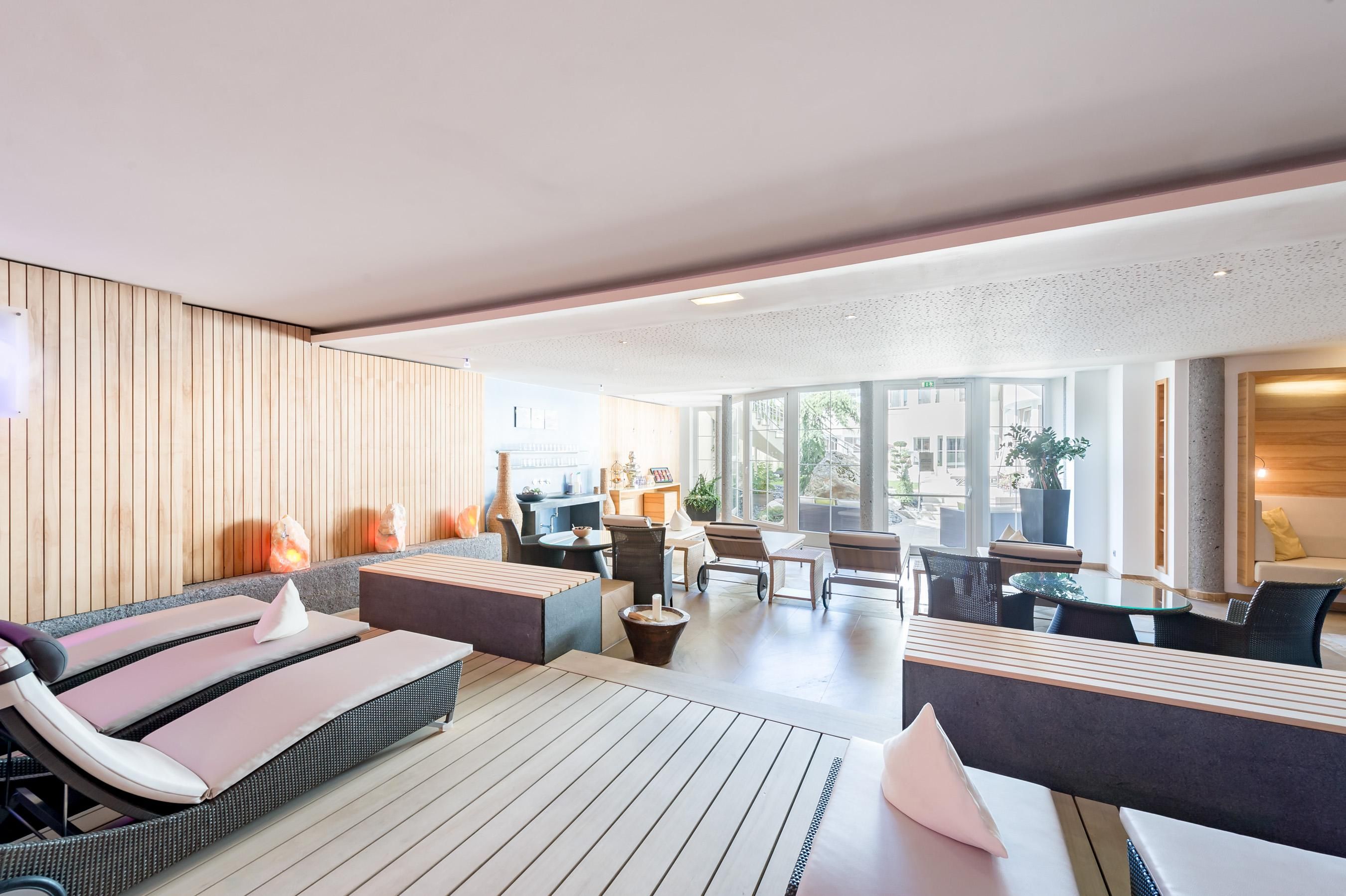 Ein modernes und stilvolles Spa mit bequemen Liegen und einem offenen Bereich. Große Fenster bieten einen Blick auf den Außenbereich.