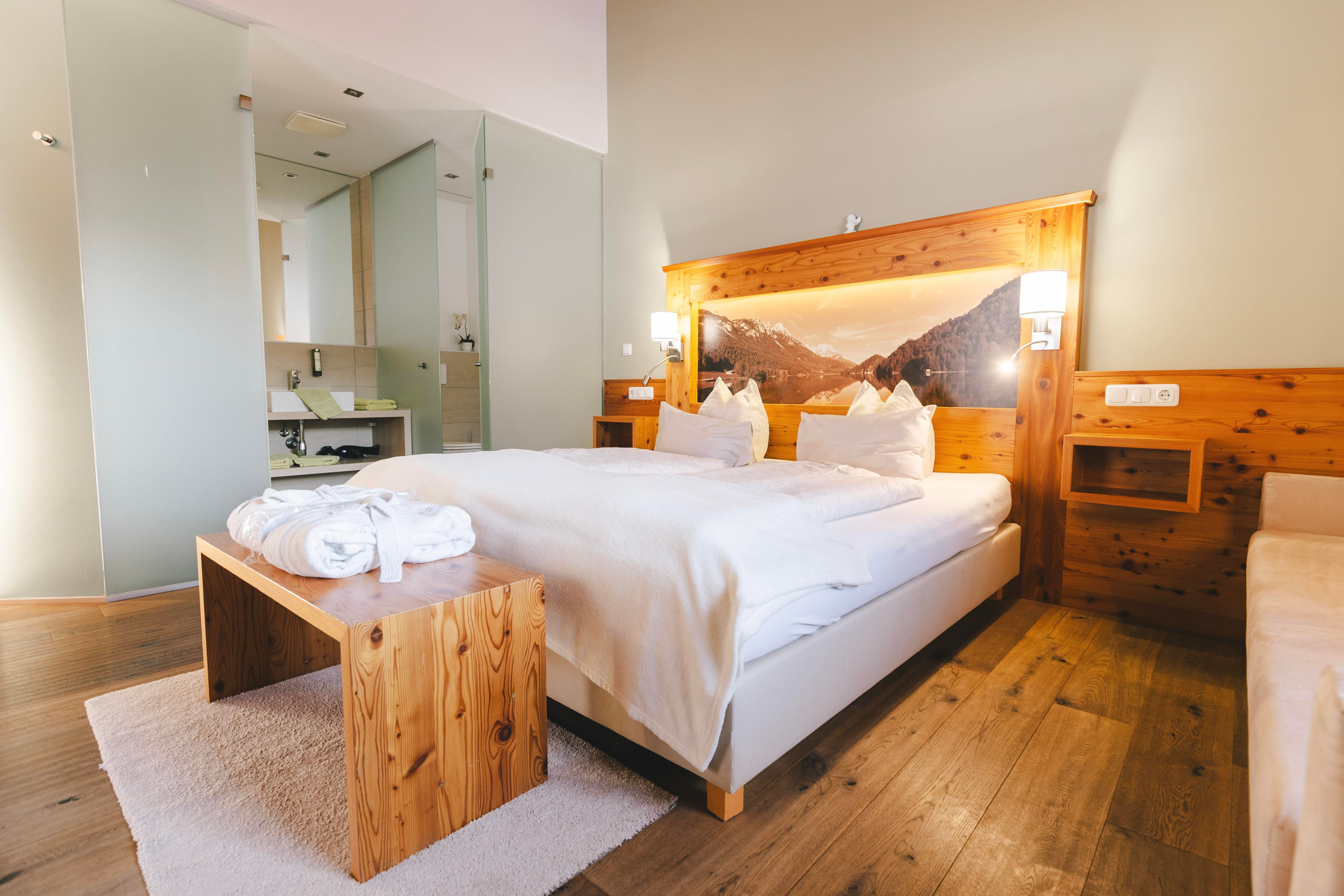 Ein gemütliches Zimmer mit einem großen Bett und Holzdetails. Das helle Ambiente schafft eine entspannende Atmosphäre.