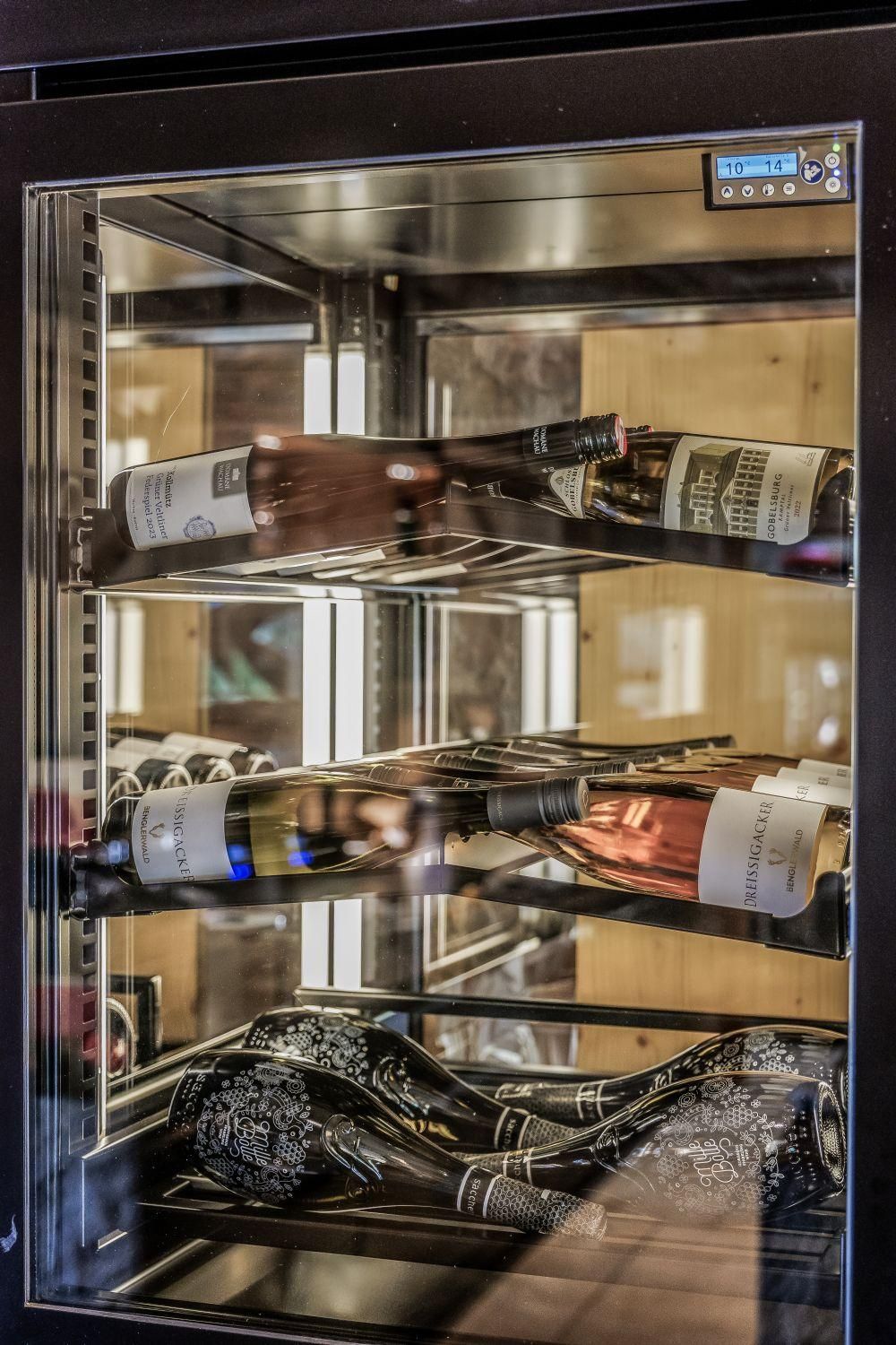Ein eleganter Weinschrank mit verschiedenen Flaschen Wein. Der Schrank zeigt eine moderne Ausstattung und ist gut beleuchtet.