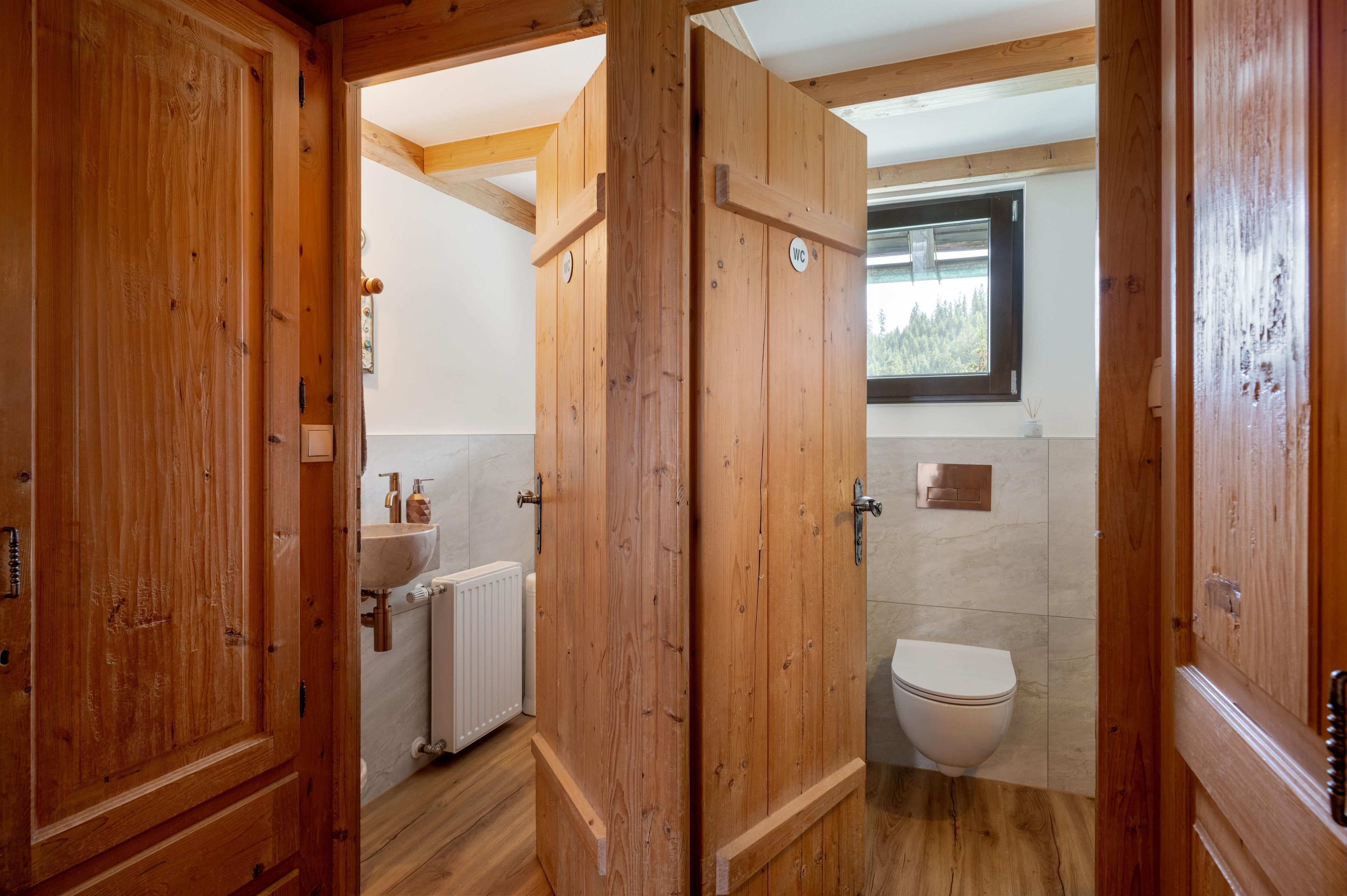 Ein modernes Badezimmer mit Holzverkleidung. Es gibt eine Toilette und eine Dusche, die durch Holzwände abgetrennt sind.