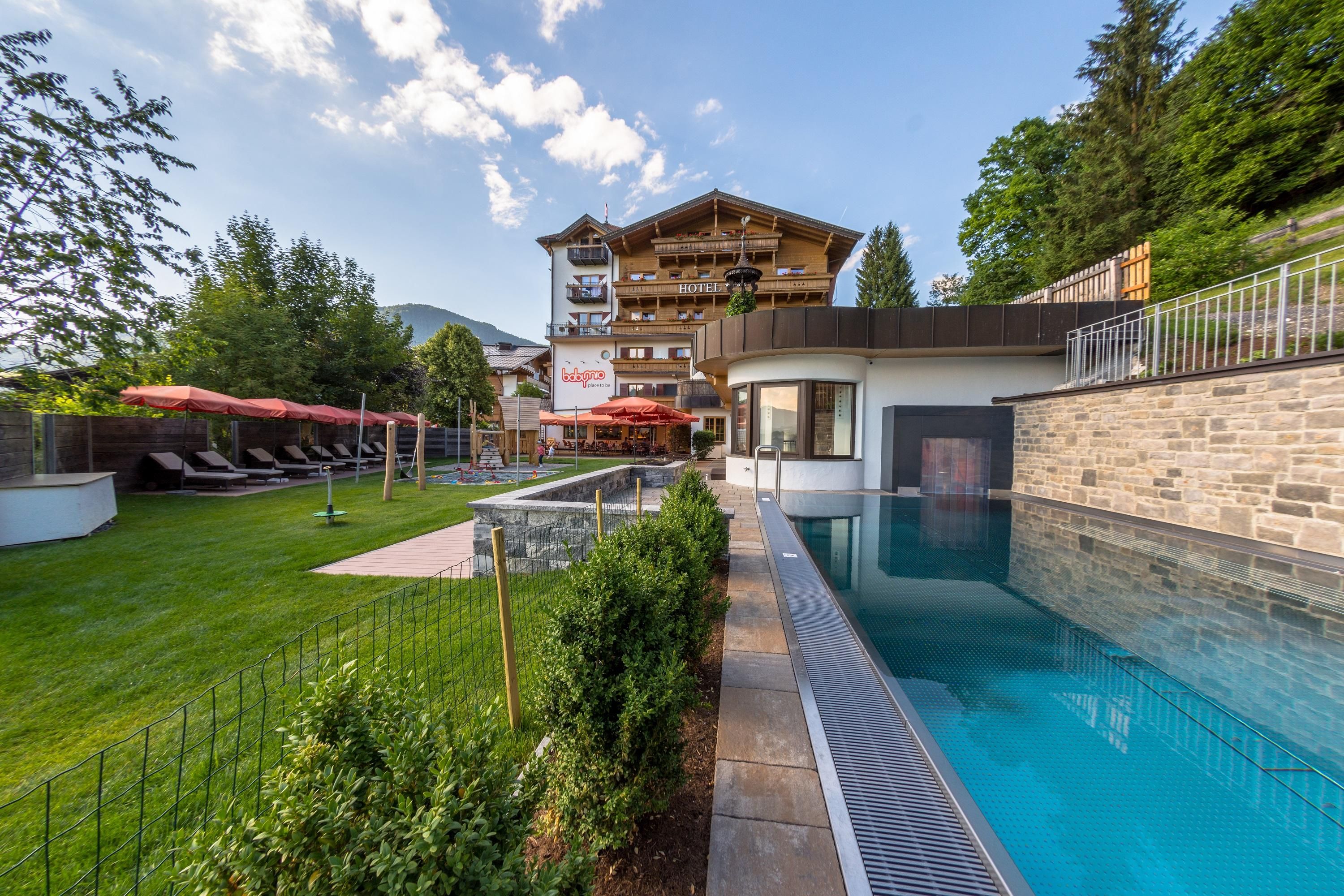 Ein schöner Außenbereich mit einem Pool und Liegen. Im Hintergrund steht ein charmantes Gebäude inmitten von Bäumen.