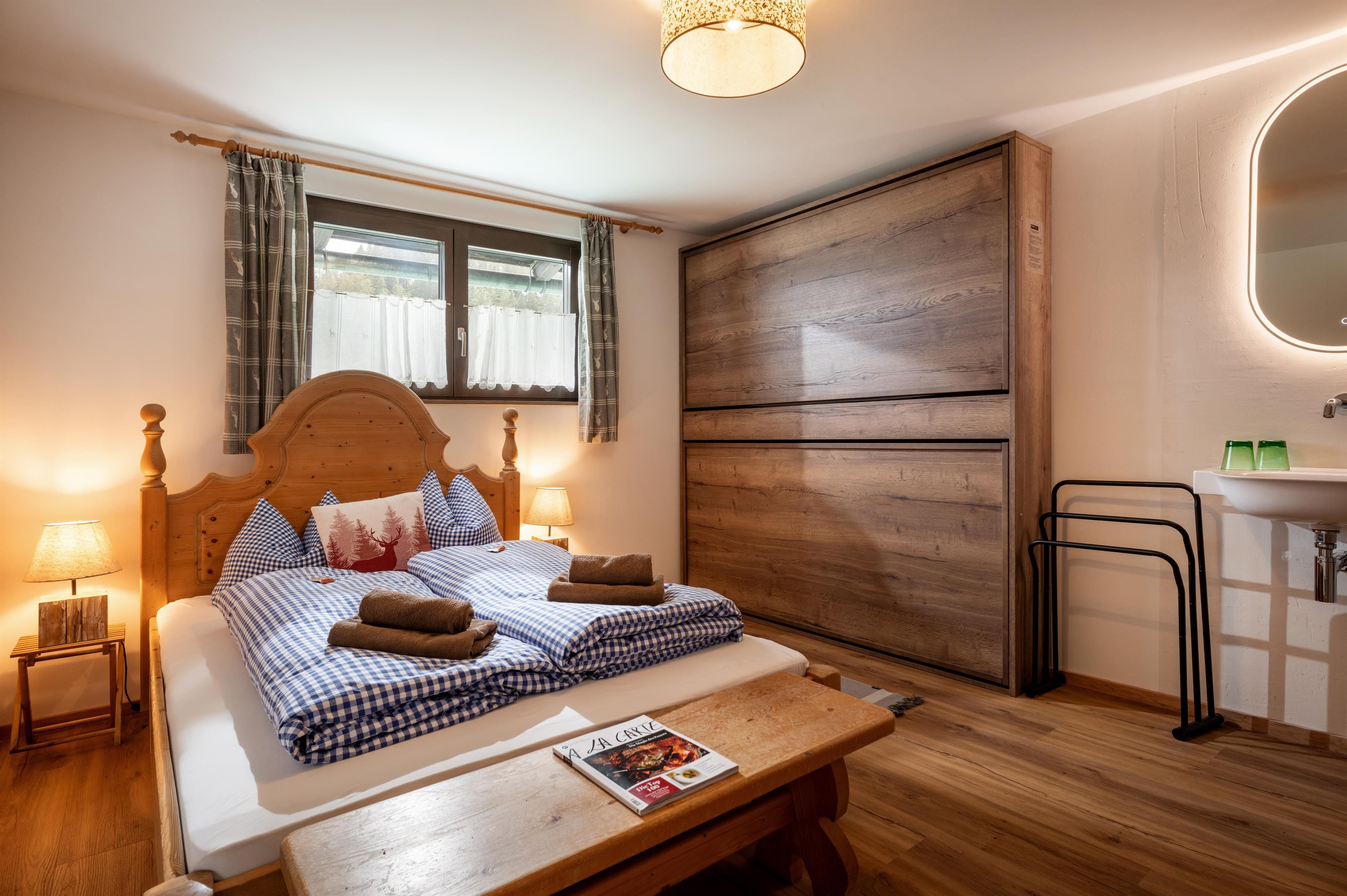Ein gemütliches Schlafzimmer mit einem großen Bett und Holzdetails. Die warmen Farben und das natürliche Licht schaffen eine einladende Atmosphäre.