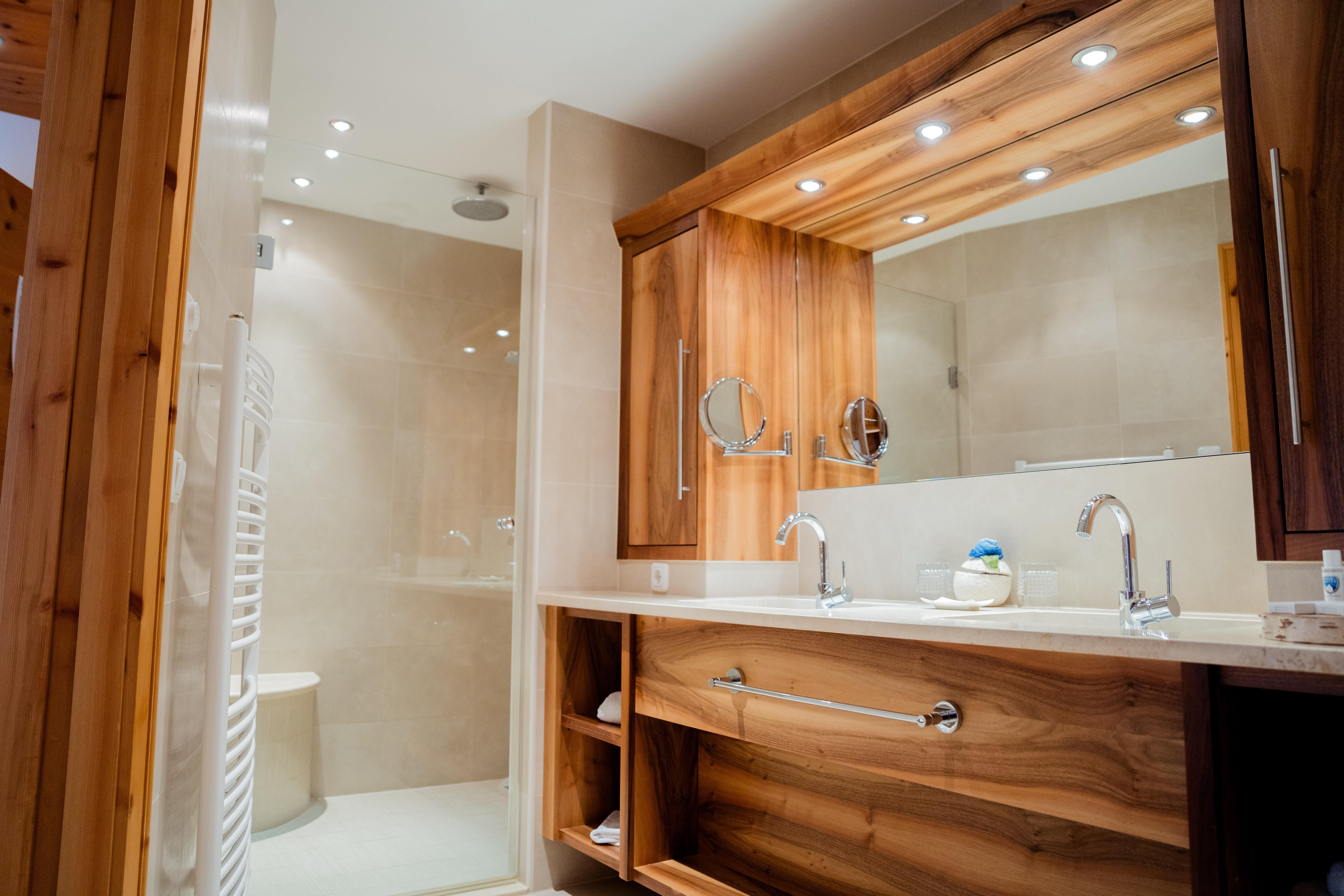 Ein modernes Badezimmer mit Holzdetails und einem Waschbecken. Die Duschkabine ist im Hintergrund gut sichtbar.