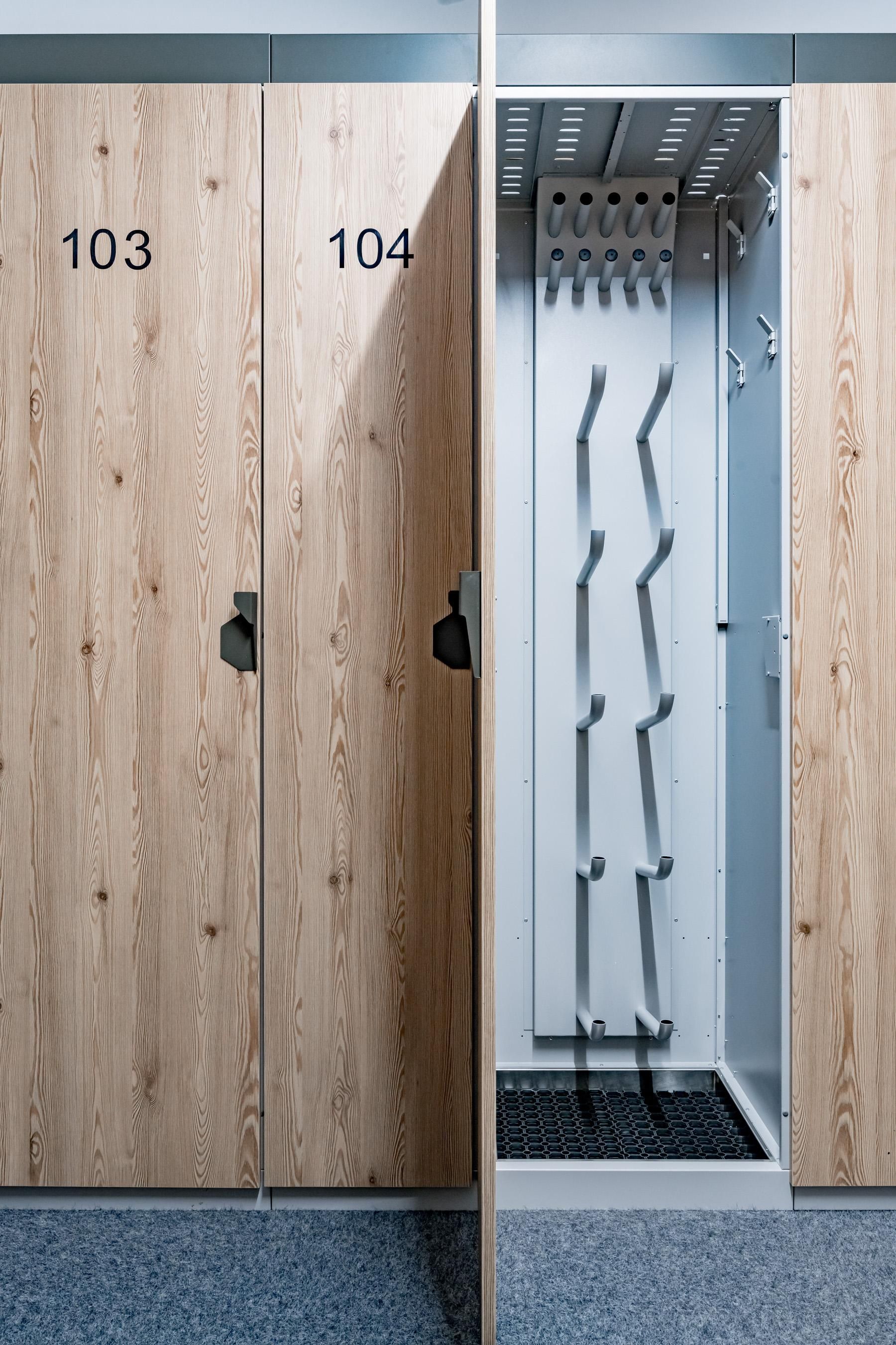 Zwei Schränke mit den Nummern 103 und 104. Ein offener Schrank zeigt Garderobenhaken und einen Bodenbelag.