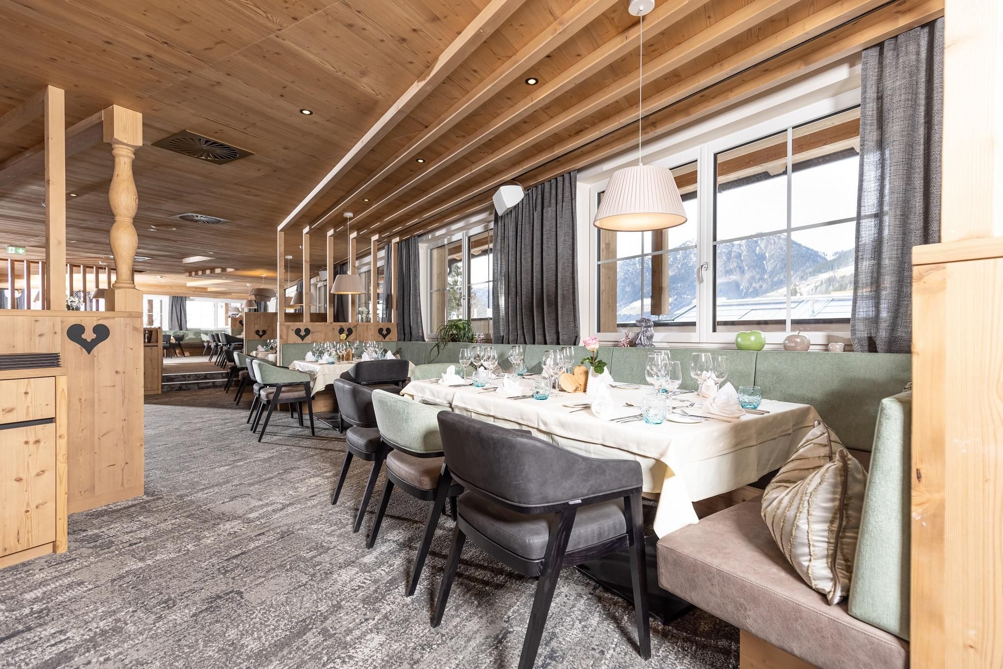 Ein gemütliches Restaurant mit Holzdekor und elegant gedeckten Tischen. Große Fenster bieten einen Blick auf die umliegende Landschaft.