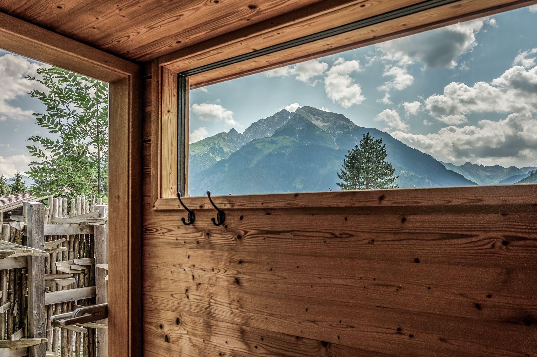 Ein Blick aus einer Sauna auf majestätische Berge und einen bewölkten Himmel. Die Natur ist friedlich und einladend.