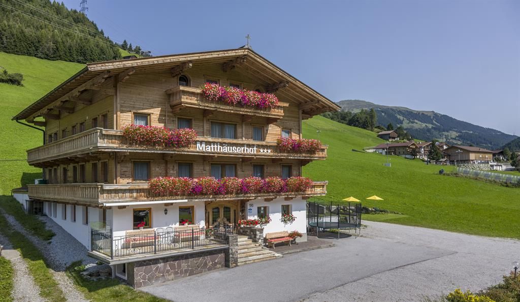 Ein charmantes, Holzhaus im alpinen Stil mit bunten Blumen. Umgeben von grünen Wiesen und Bergen, bietet es eine einladende Atmosphäre.