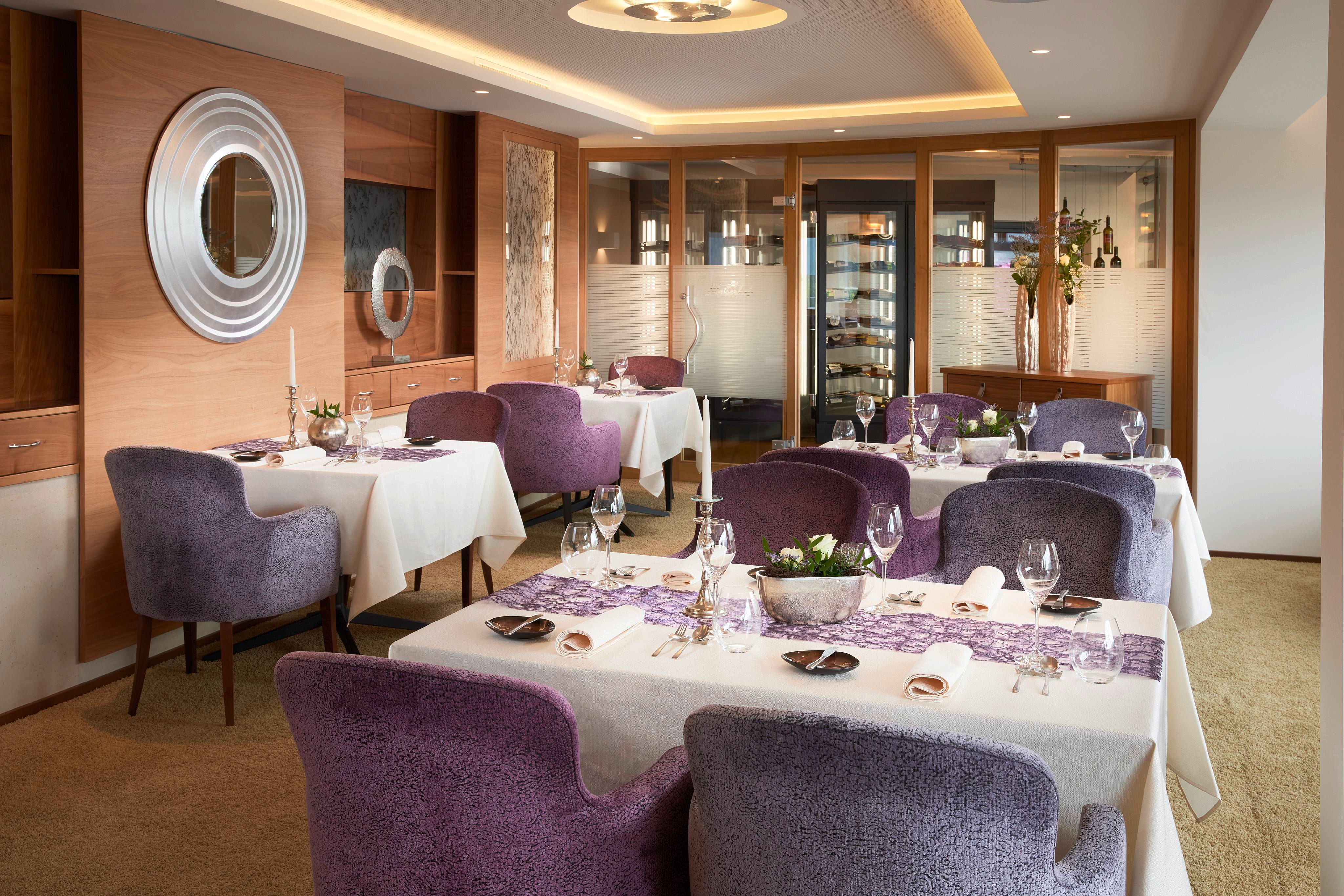 Ein elegantes Restaurant mit modernen Möbeln und gedeckten Tischen. Die Wände sind mit warmen Holztönen und stilvollen Akzenten gestaltet.