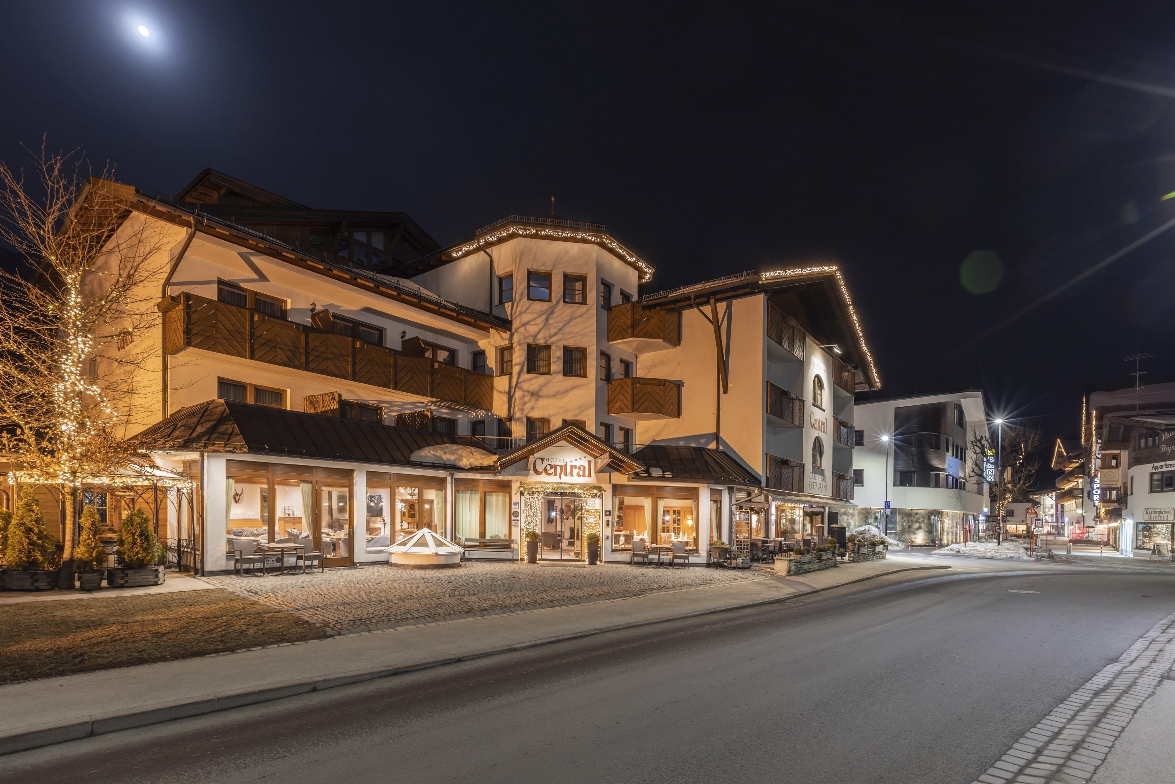 Ein charmantes Hotel mit festlicher Beleuchtung bei Nacht. Die Straße ist ruhig und einladend, umgeben von modernen Gebäuden.