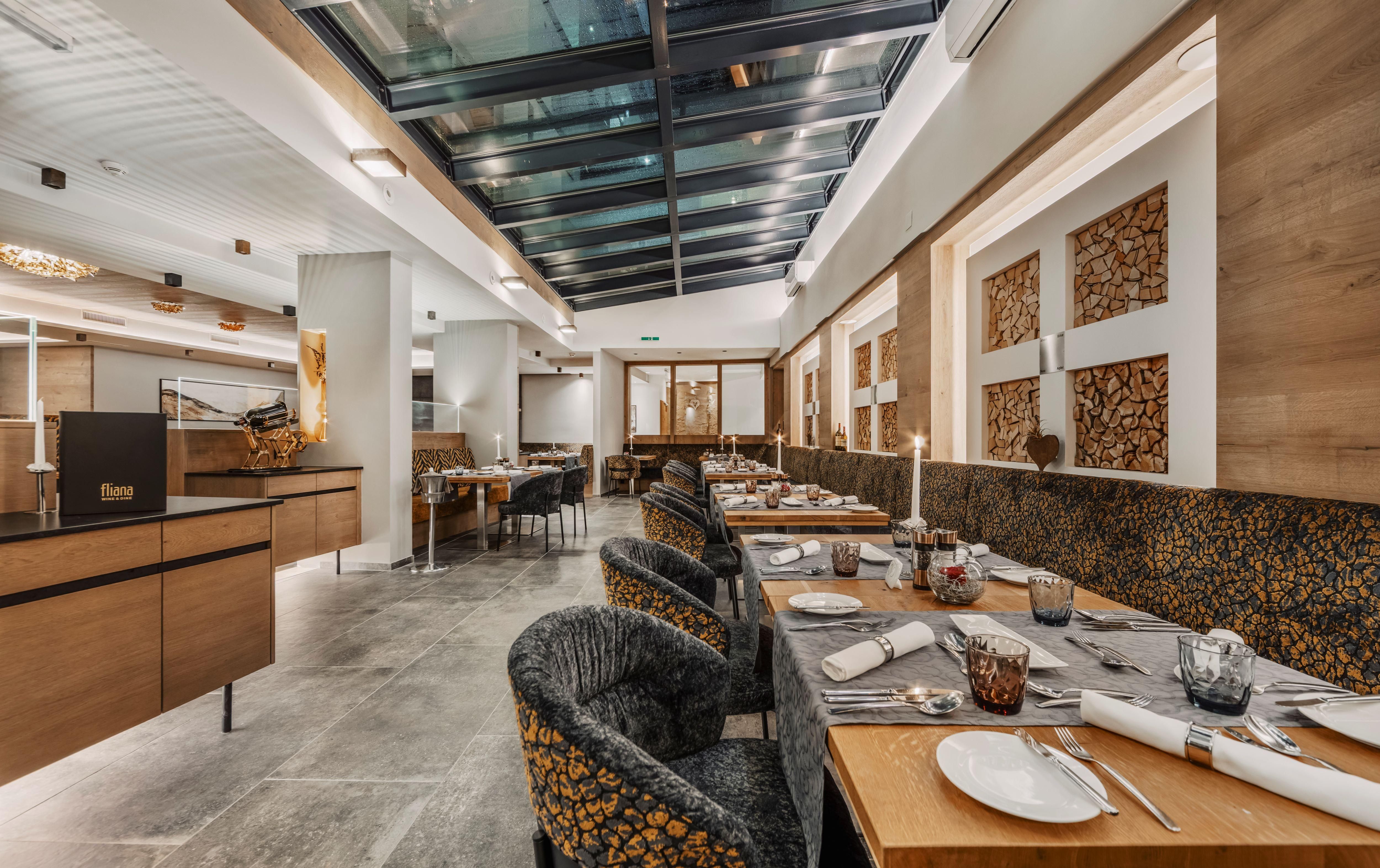 Ein modernes Restaurant mit eleganten Tischen und Stühlen. Große Fenster sorgen für viel Tageslicht und eine einladende Atmosphäre.