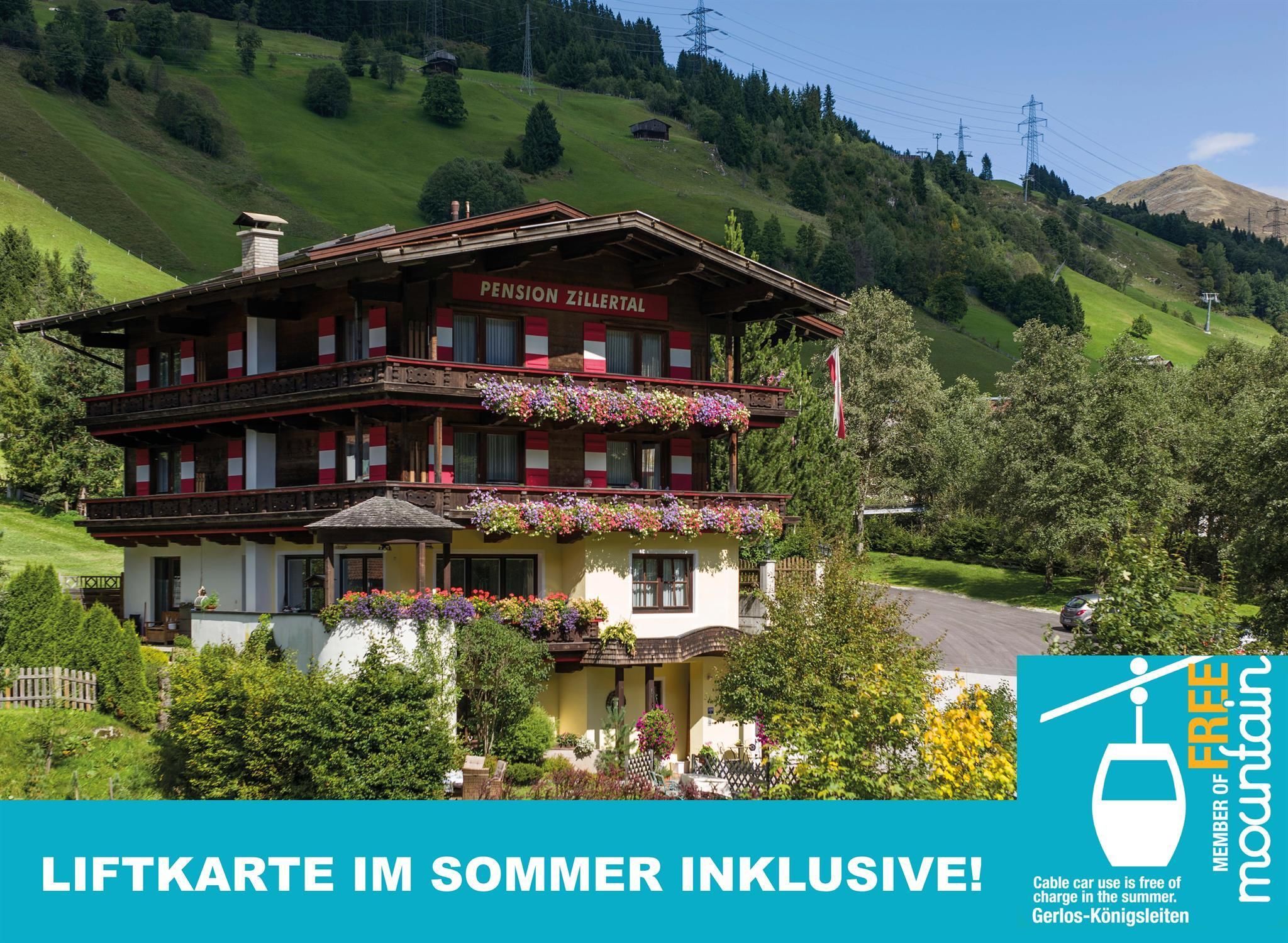 Ein malerisches Ferienhaus mit blühenden Balkonen in einer grünen Berglandschaft. Die Umgebung ist idyllisch und einladend.