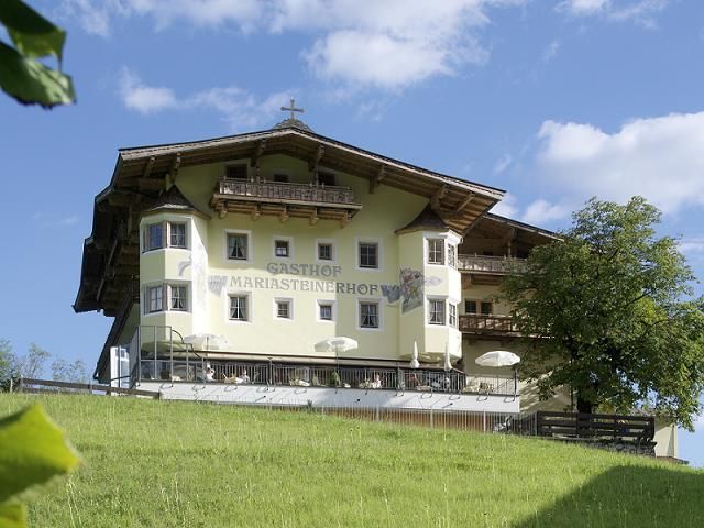 Ein schönes Haus auf einer grünen Wiese unter einem blauen Himmel. Umgeben von Bäumen strahlt die Szene Ruhe und Idylle aus.