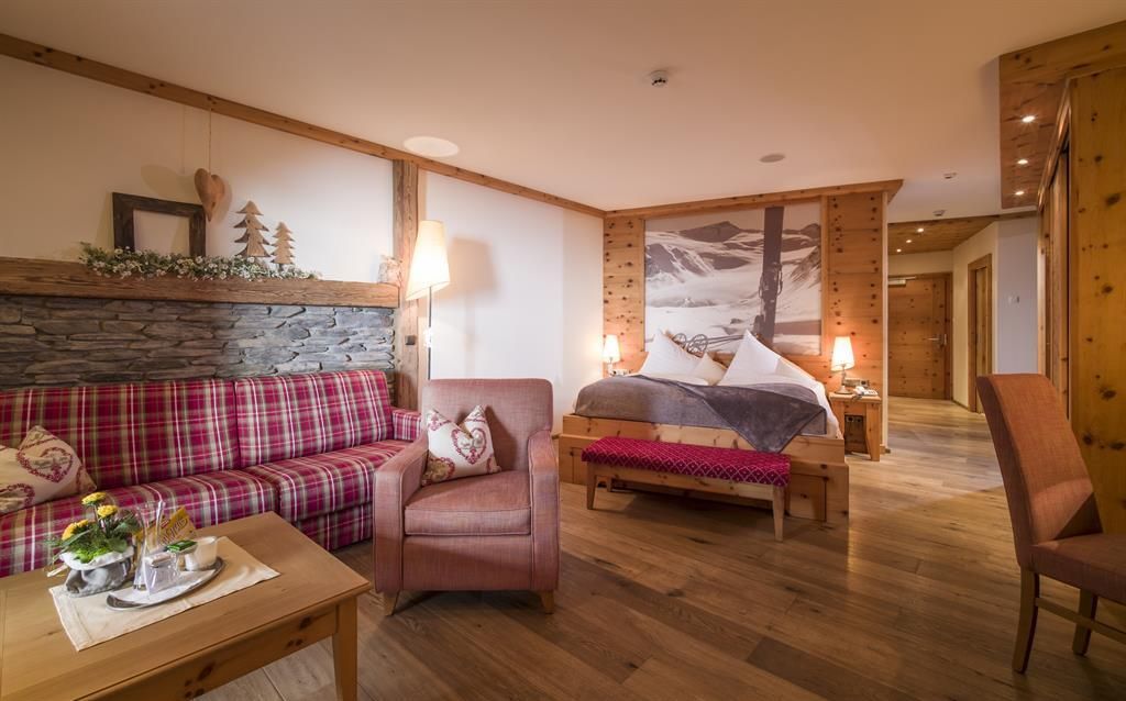Ein gemütliches Hotelzimmer mit Holzvertäfelung und rustikalem Design. Gemütliche Möbel und eine schöne Aussicht auf die Berge schaffen eine einladende Atmosphäre.