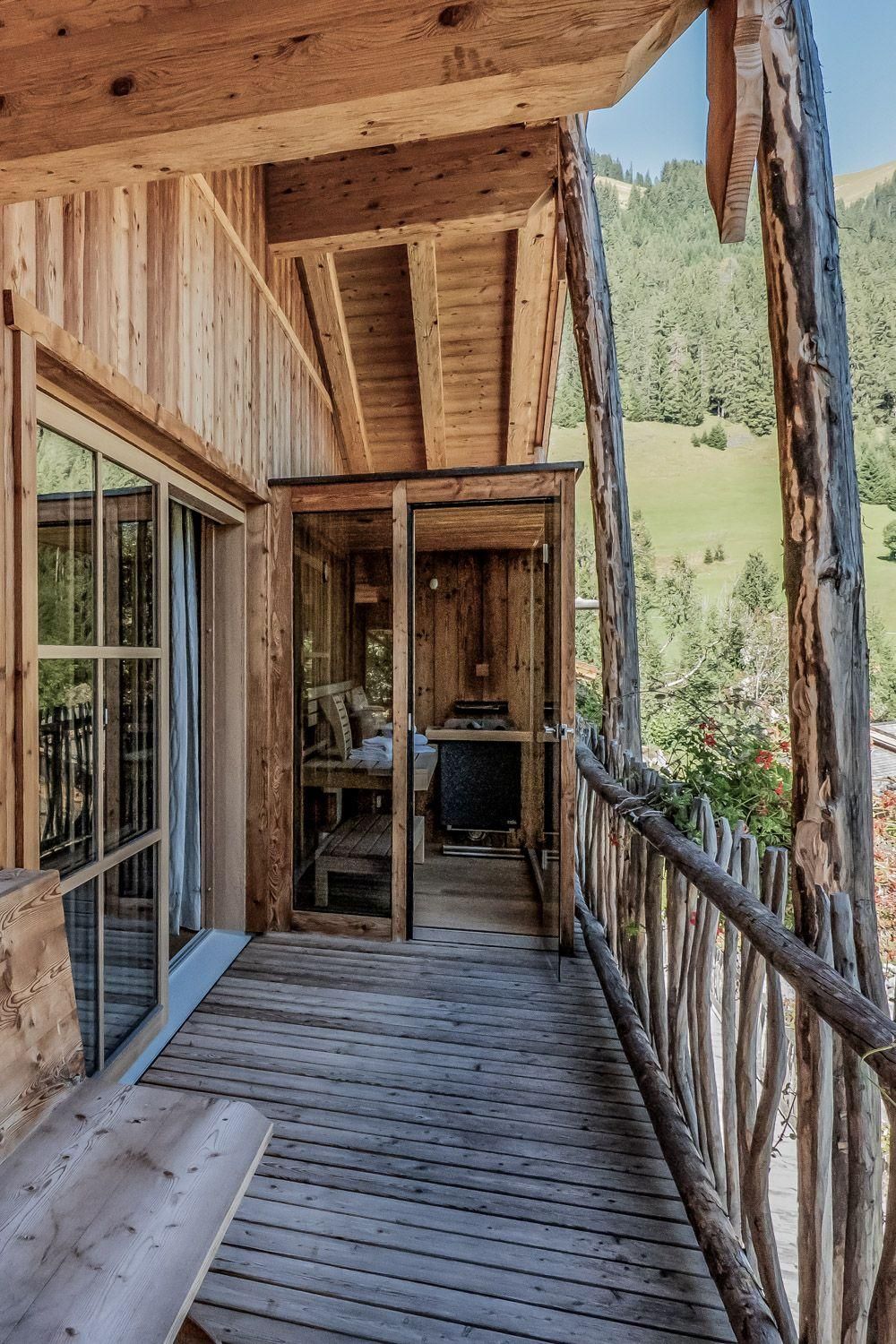 Ein gemütlicher Balkon aus Holz mit schöner Aussicht auf die grüne Landschaft. Der Balkon ist mit einem kleinen Tisch und Stühlen und einer Sauna ausgestattet.