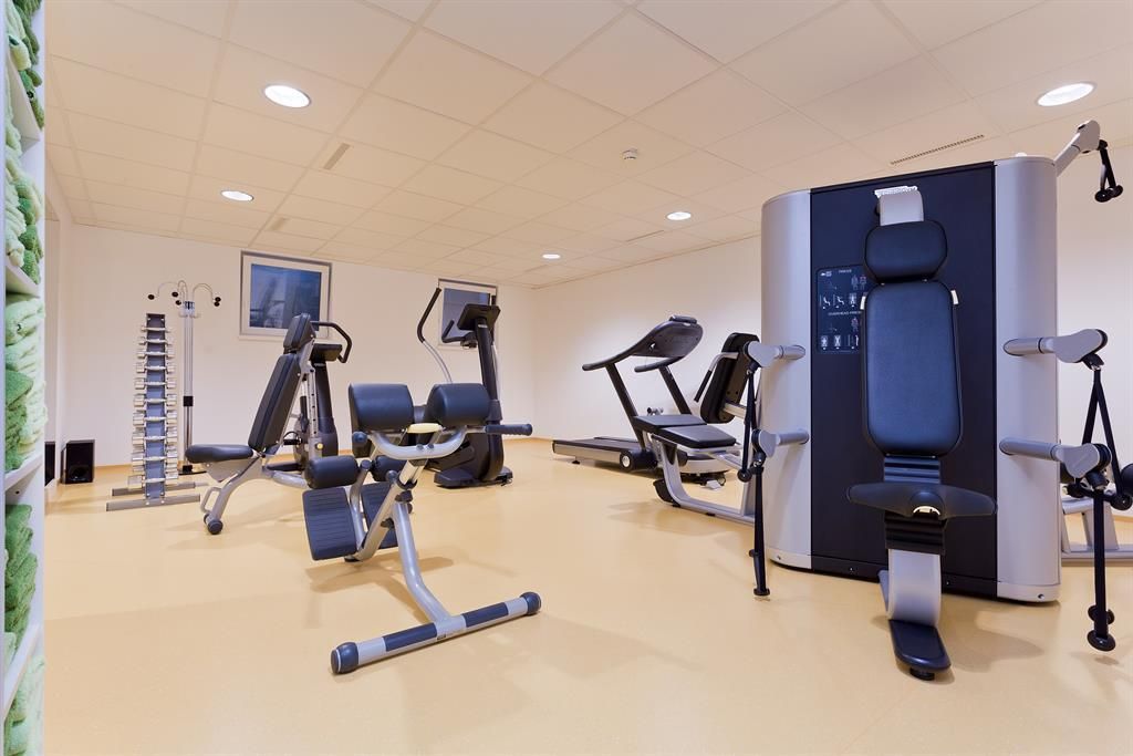 Ein gut ausgestatteter Fitnessraum mit verschiedenen Trainingsgeräten. Der Raum hat einen hellen Boden und eine angenehme Atmosphäre.