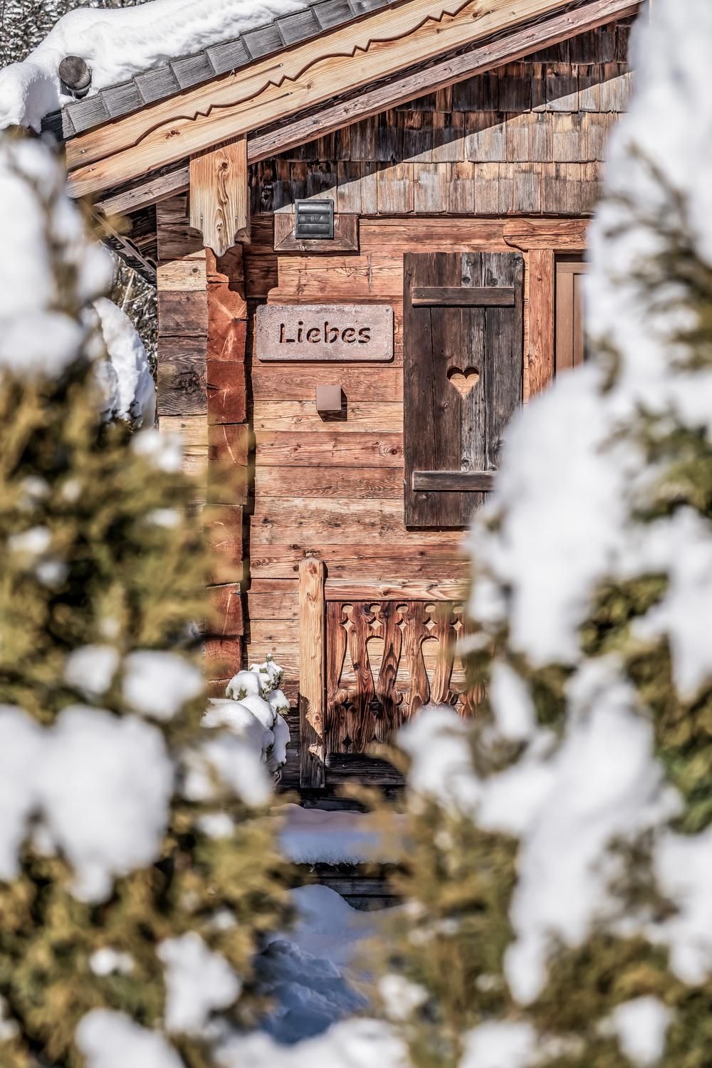 Eine gemütliche Chalet im Schnee mit einem Herz im Fenster.