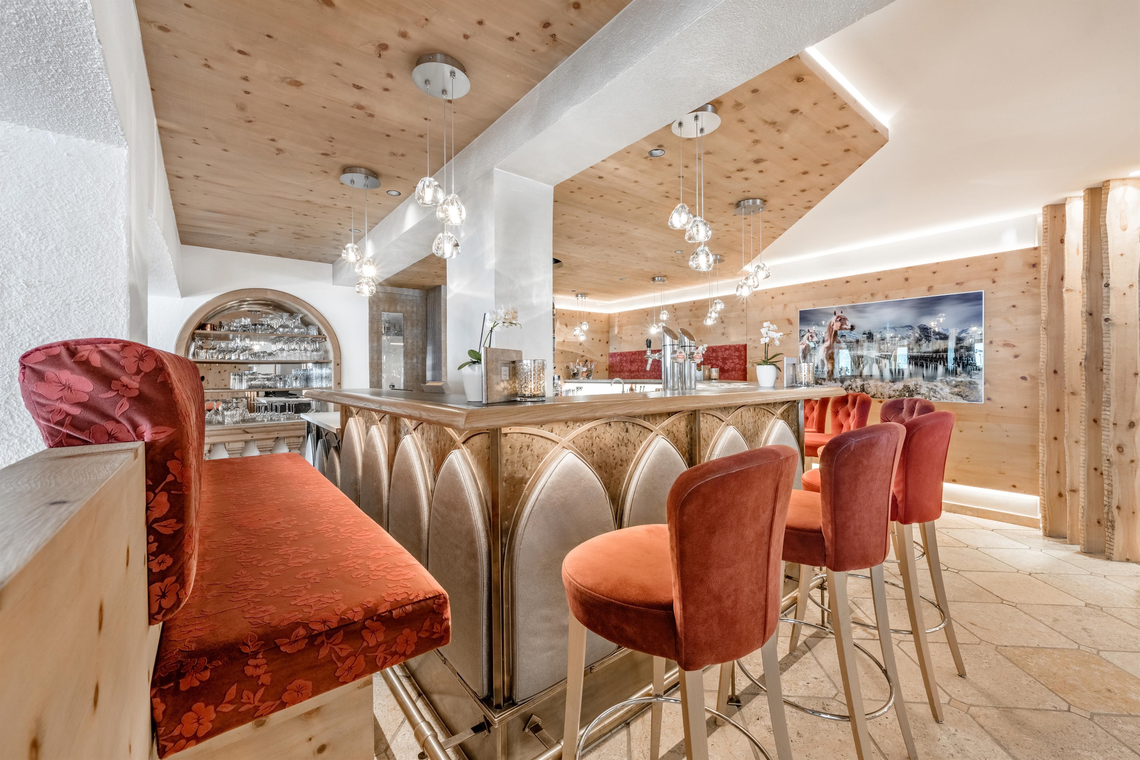 Eine stilvolle Bar mit eleganten roten Stühlen und einer Holzdecke. Chemische und gemütliche Beleuchtung sorgt für eine einladende Atmosphäre.