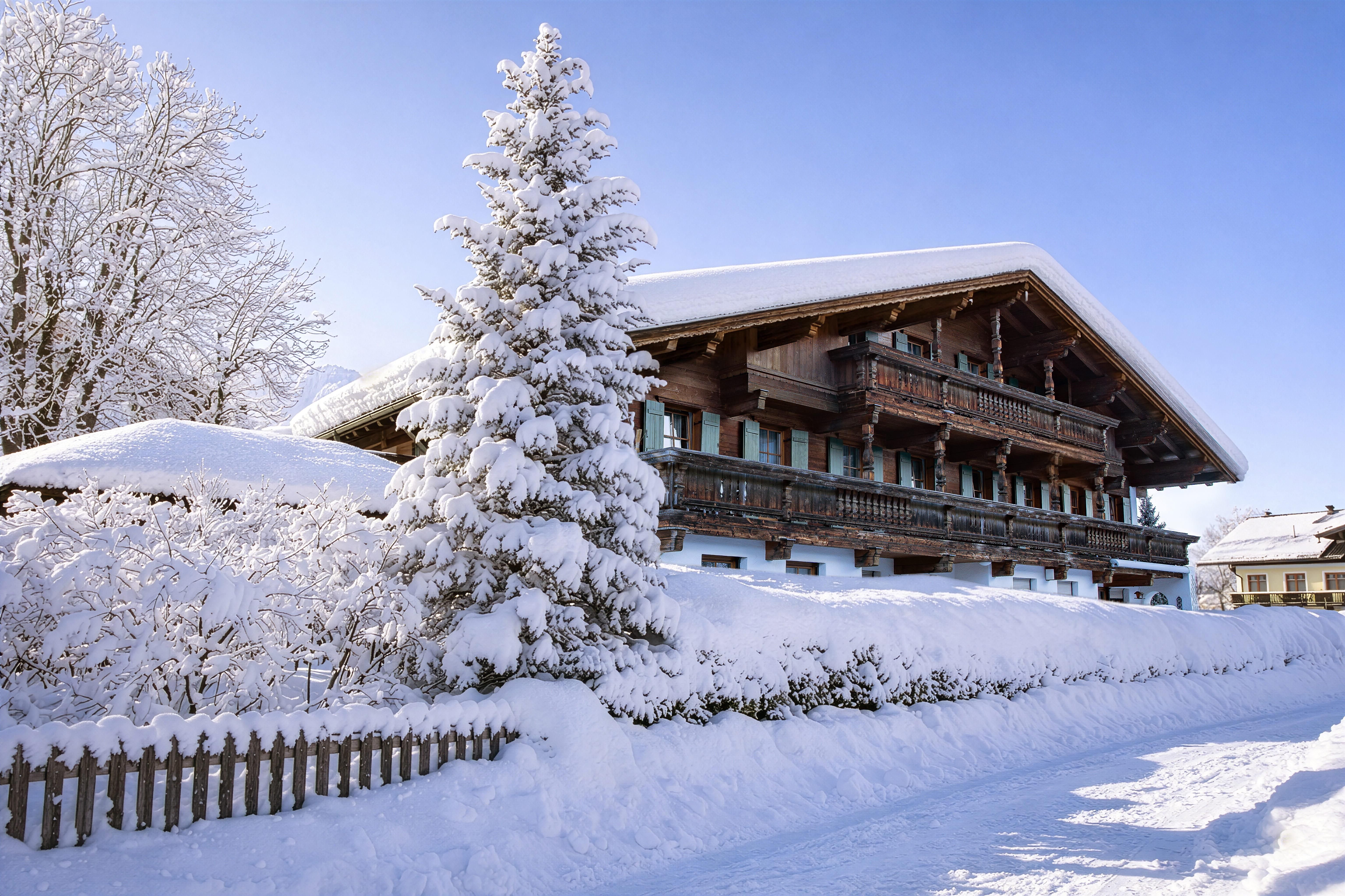 Ein wunderschönes Chalet im Winter mit schneebedecktem Dach und Bäumen. Der klare blaue Himmel verleiht der Szene eine friedliche Atmosphäre.