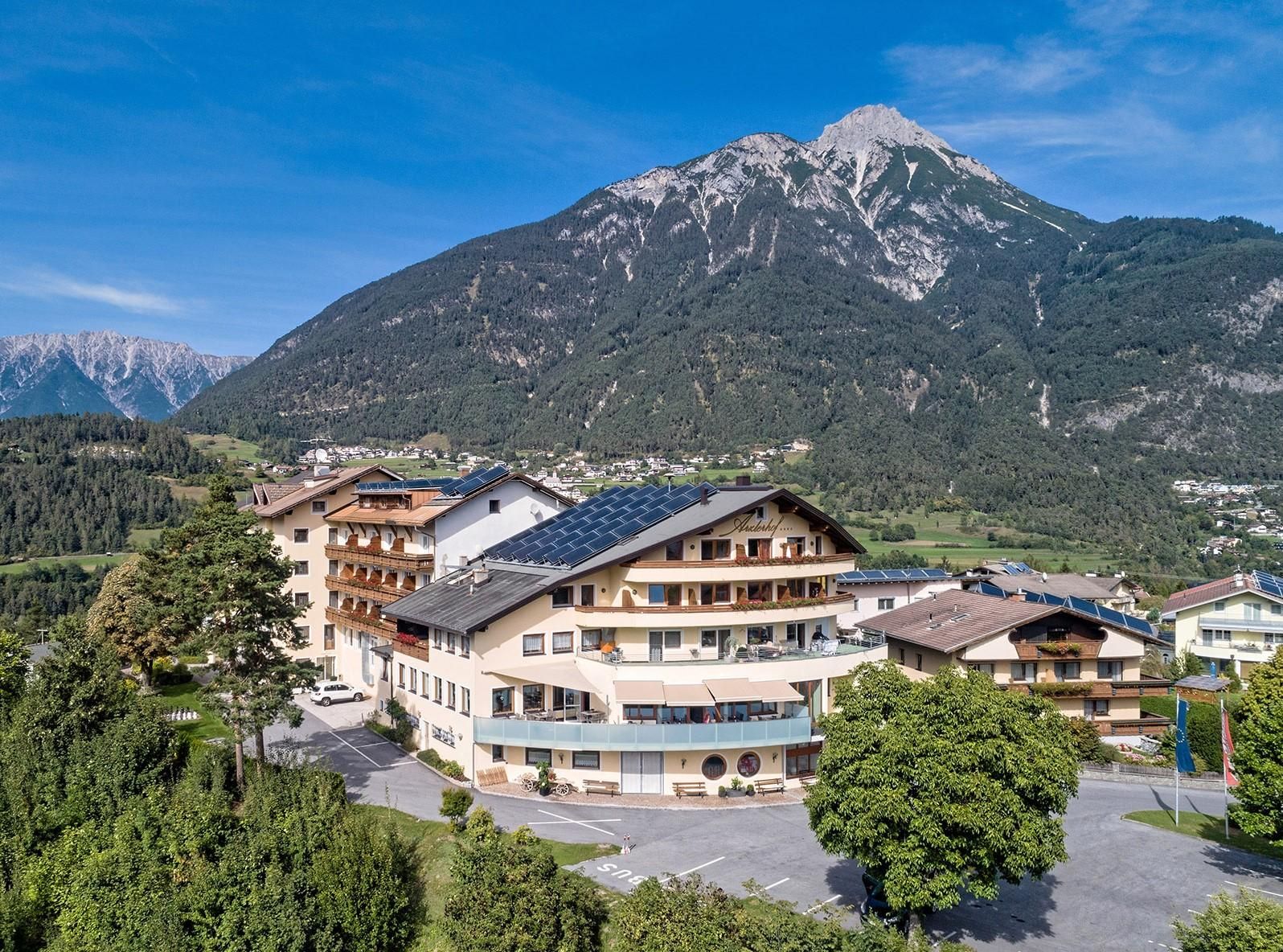 Ein charmantes Hotel mit modernen Annehmlichkeiten, umgeben von grünen Wäldern und beeindruckenden Bergen. Der klare Himmel bietet eine malerische Aussicht auf die Natur.