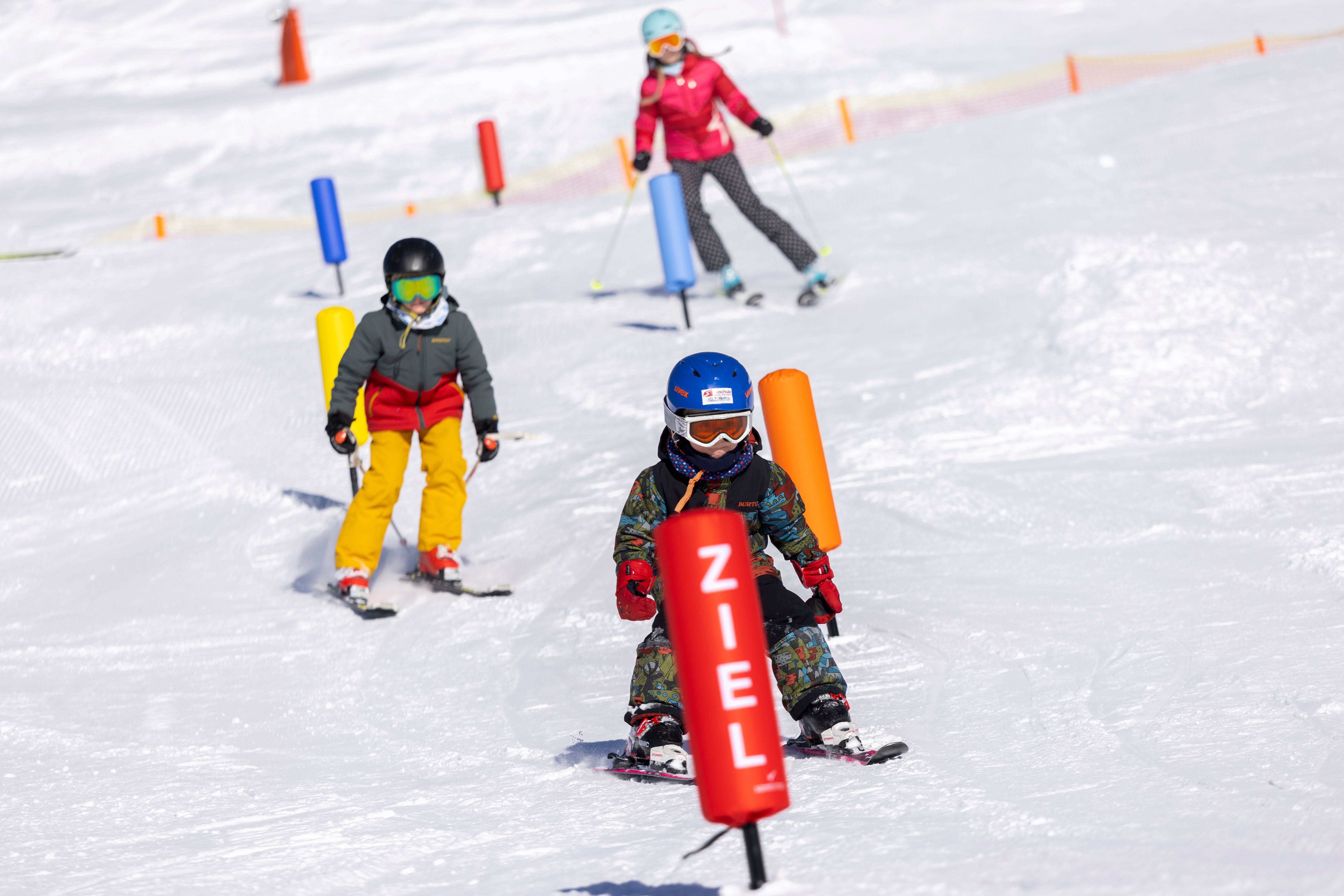 Familien Skifahren am Zettersfeld bei Lienz. Kinder fahren Ski durch Slalomstangen.