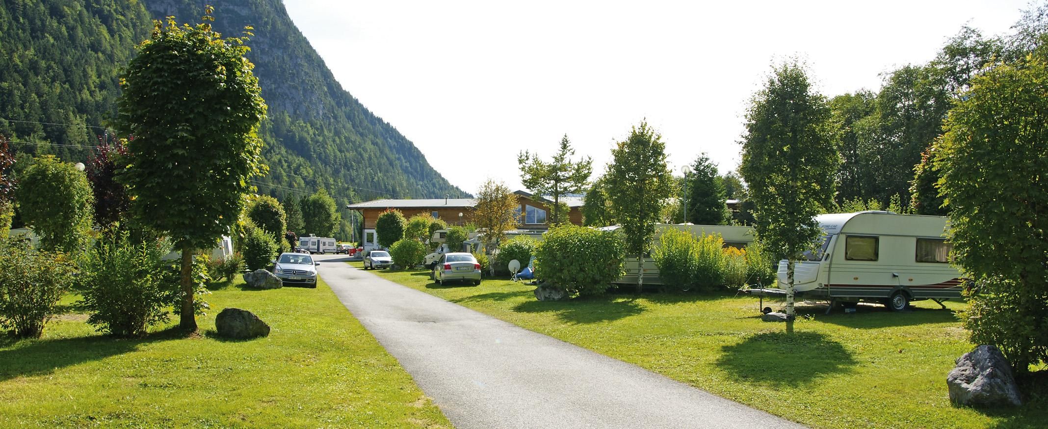 Ein schöner Campingplatz mit Wohnwagen und viel Grün. Umgeben von Bergen und Bäumen bietet er eine ruhige Atmosphäre.