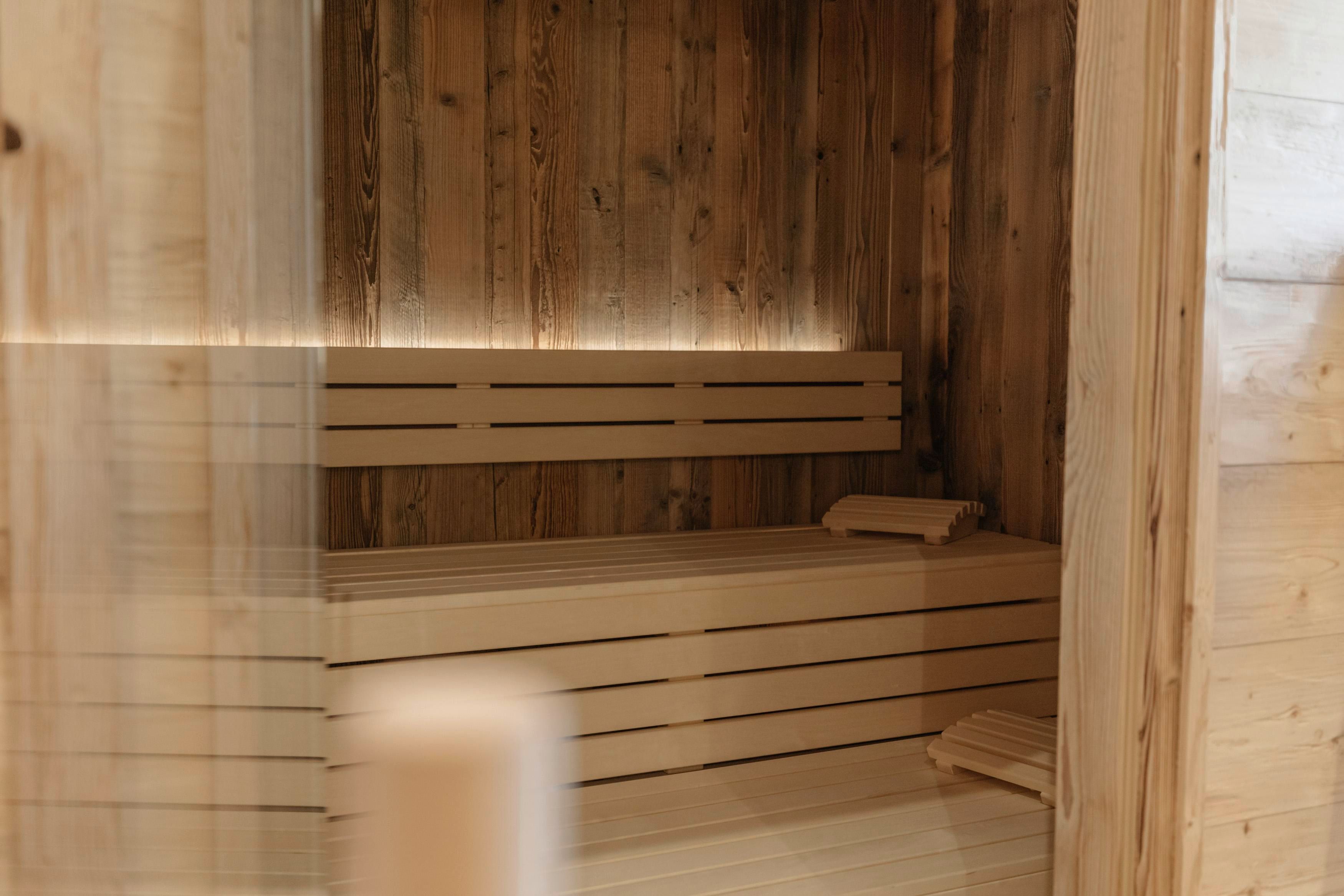 Eine moderne Sauna aus Holz mit einer gemütlichen Bank und weichen Handtüchern. Sanftes Licht sorgt für eine entspannende Atmosphäre.