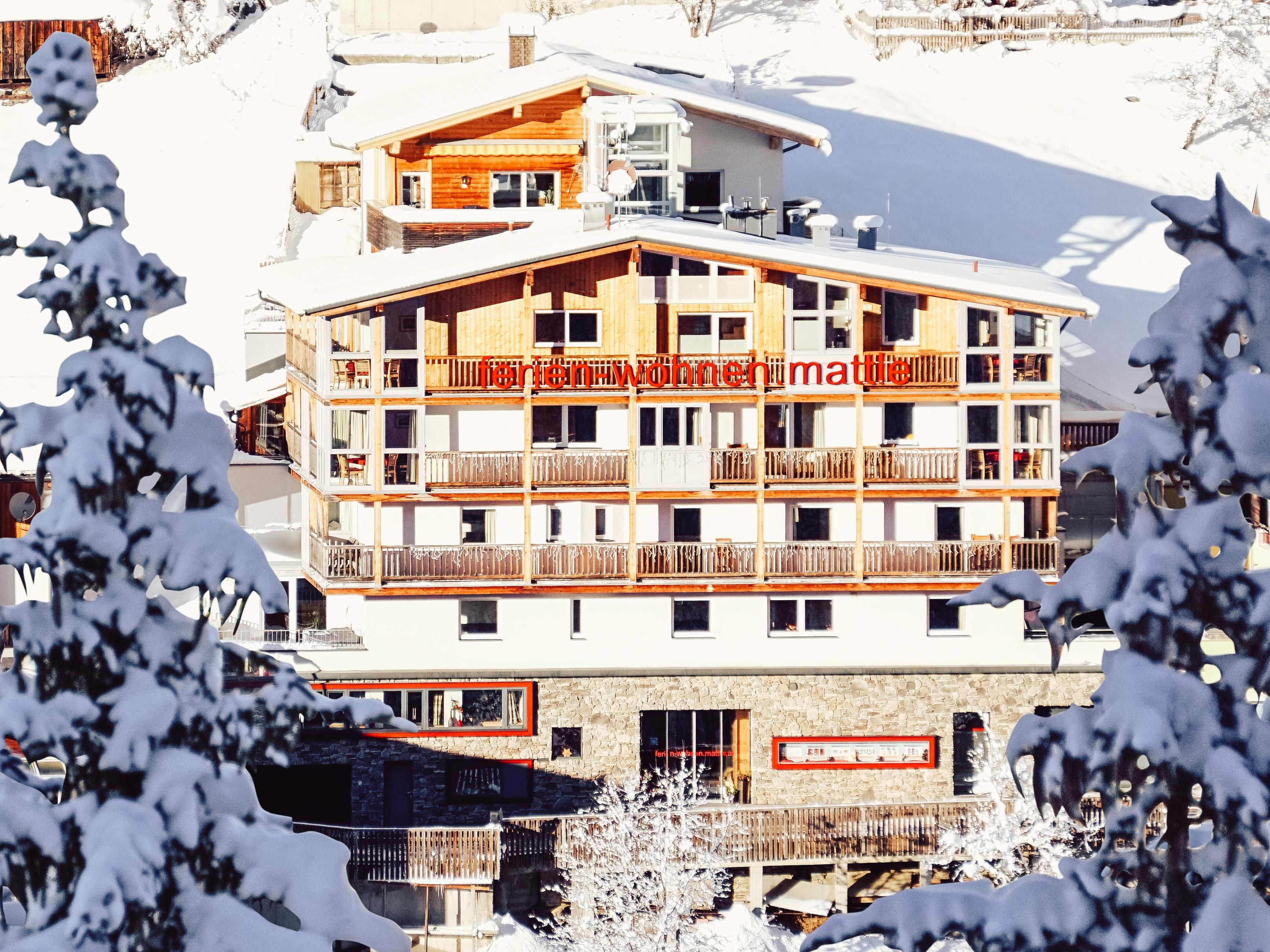 Ein modernes Chalet in einer verschneiten Landschaft. Umgeben von Bäumen und einer ruhigen Atmosphäre ist es ideal für einen Winterurlaub.