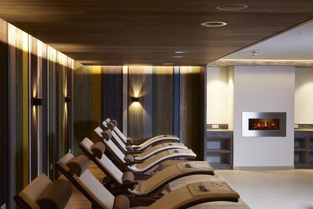 Ein modernes Spa mit bequemen Liegen und sanfter Beleuchtung. Die Wände sind in warmen Farben gestaltet, die eine entspannte Atmosphäre schaffen.