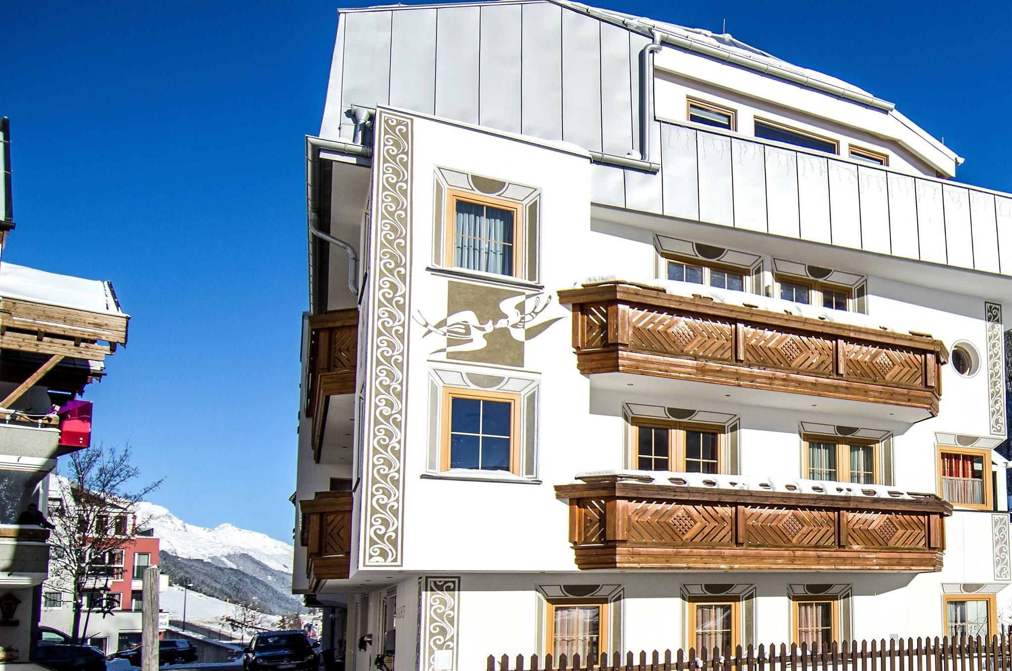 Ein modernes Gebäude mit traditionellem Holzbalustraden und eleganter Architektur. Der Himmel ist klar und blau, was eine freundliche Atmosphäre schafft.