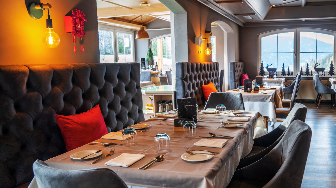Ein elegantes Restaurant mit stilvollen Tischen und gepolsterten Sitzgelegenheiten. Große Fenster bieten einen Blick auf die Umgebung.