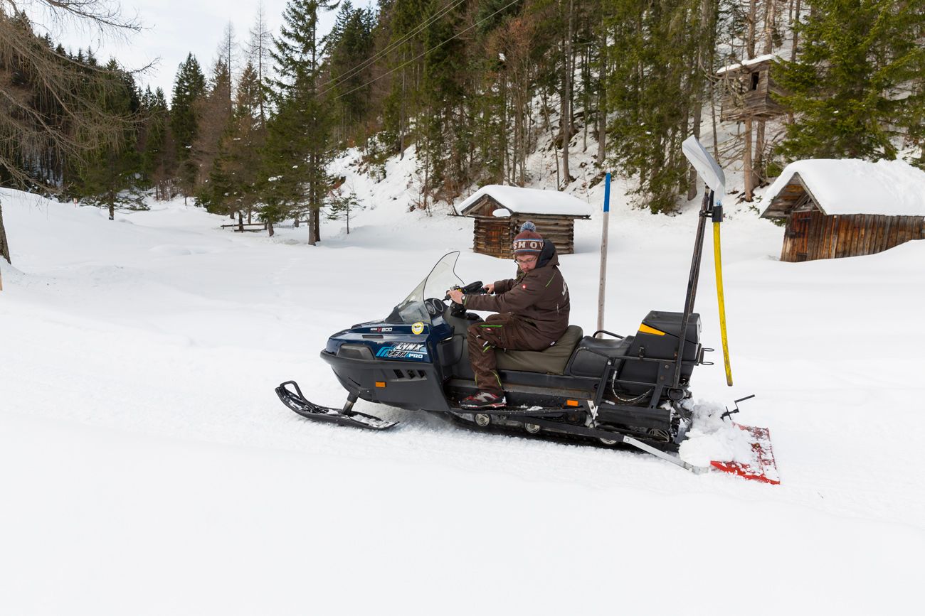 Mann auf Skidoo, walzt Schnee und präpariert Winterwanderweg