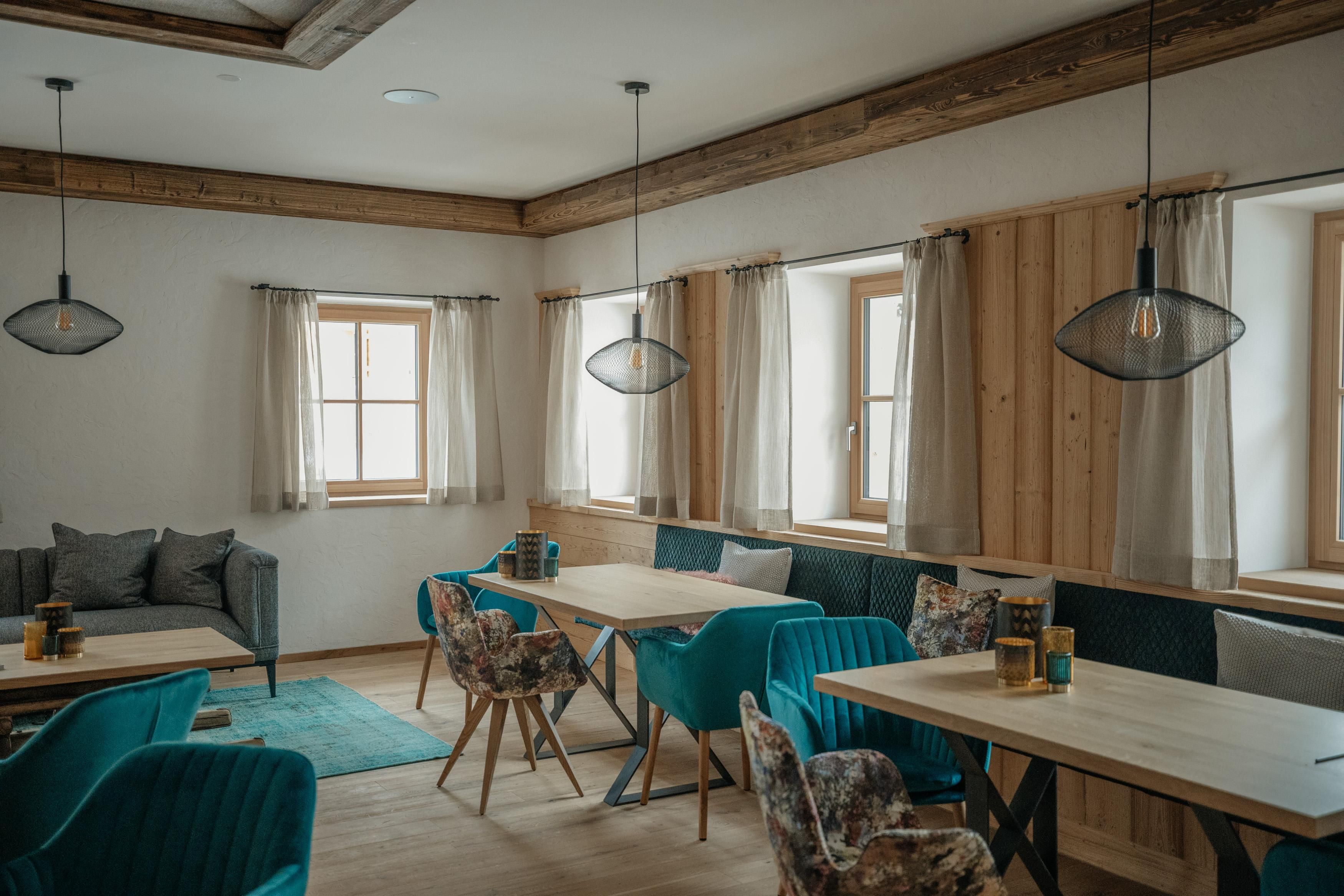 Ein modernes Café mit hellen Fenstern und stilvollen Möbeln. Die Inneneinrichtung kombiniert Holz und verschiedene Sitzgelegenheiten für eine gemütliche Atmosphäre.