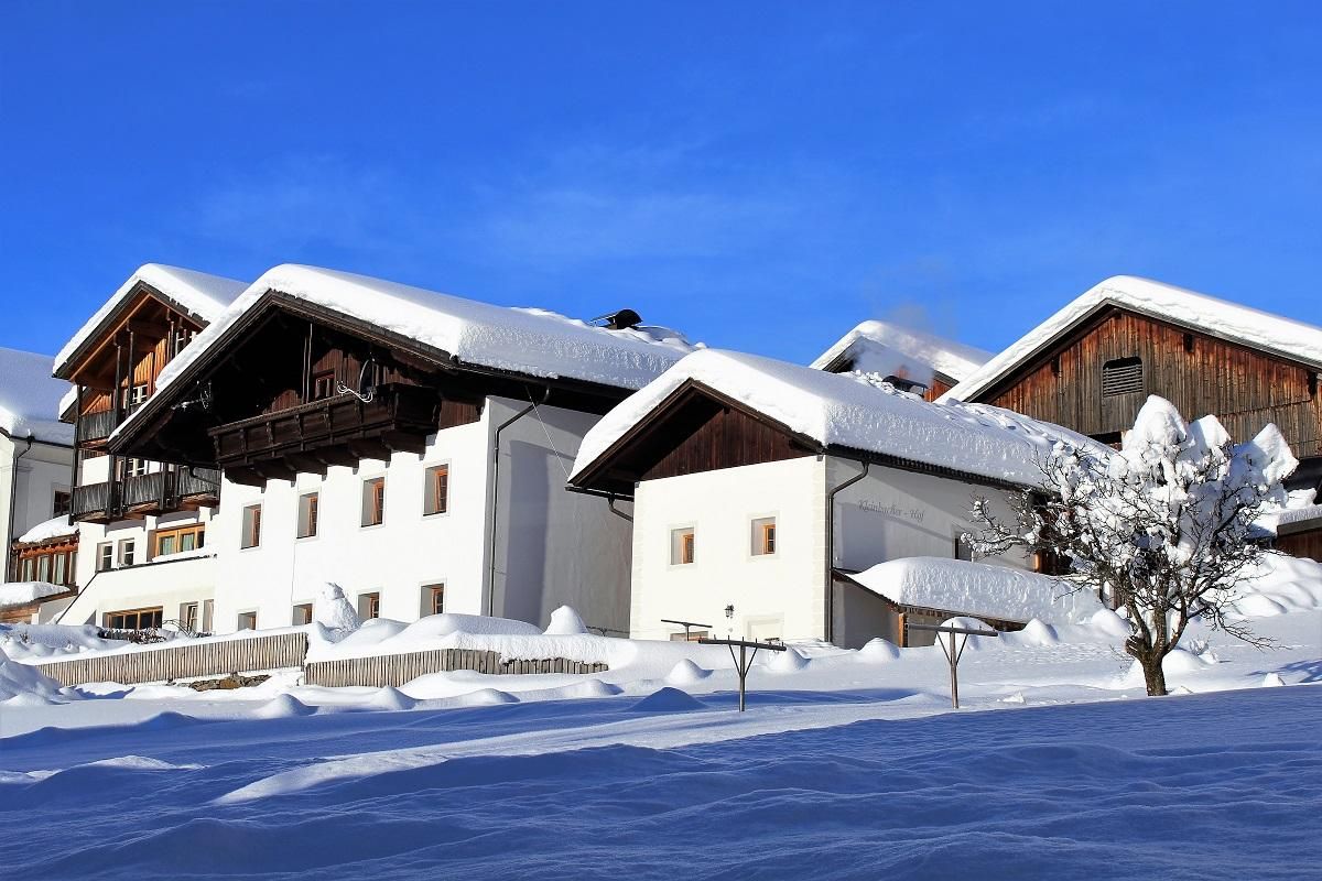 Kornkasten und Bauernhaus im Winter mit reichlich Schnee
