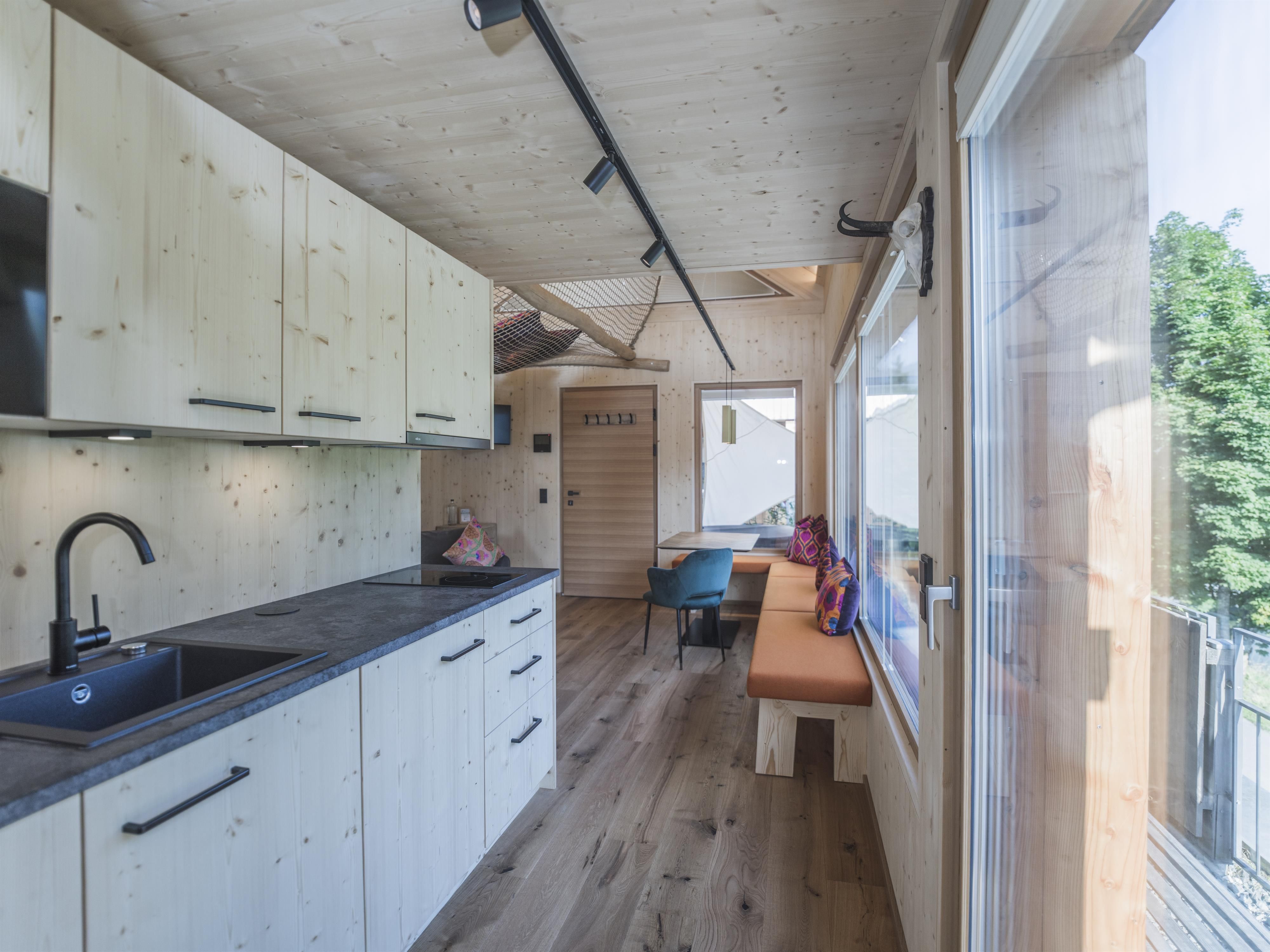 Eine moderne, helle Küche mit Holzverkleidung und großen Fenstern. Die Einrichtung ist minimalistisch mit einem schönen Blick nach draußen.