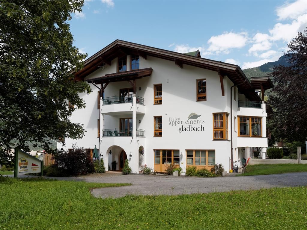 Ein charmantes Gebäude mit mehreren Etagen und Balkon. Umgeben von grünen Wiesen und Bäumen.