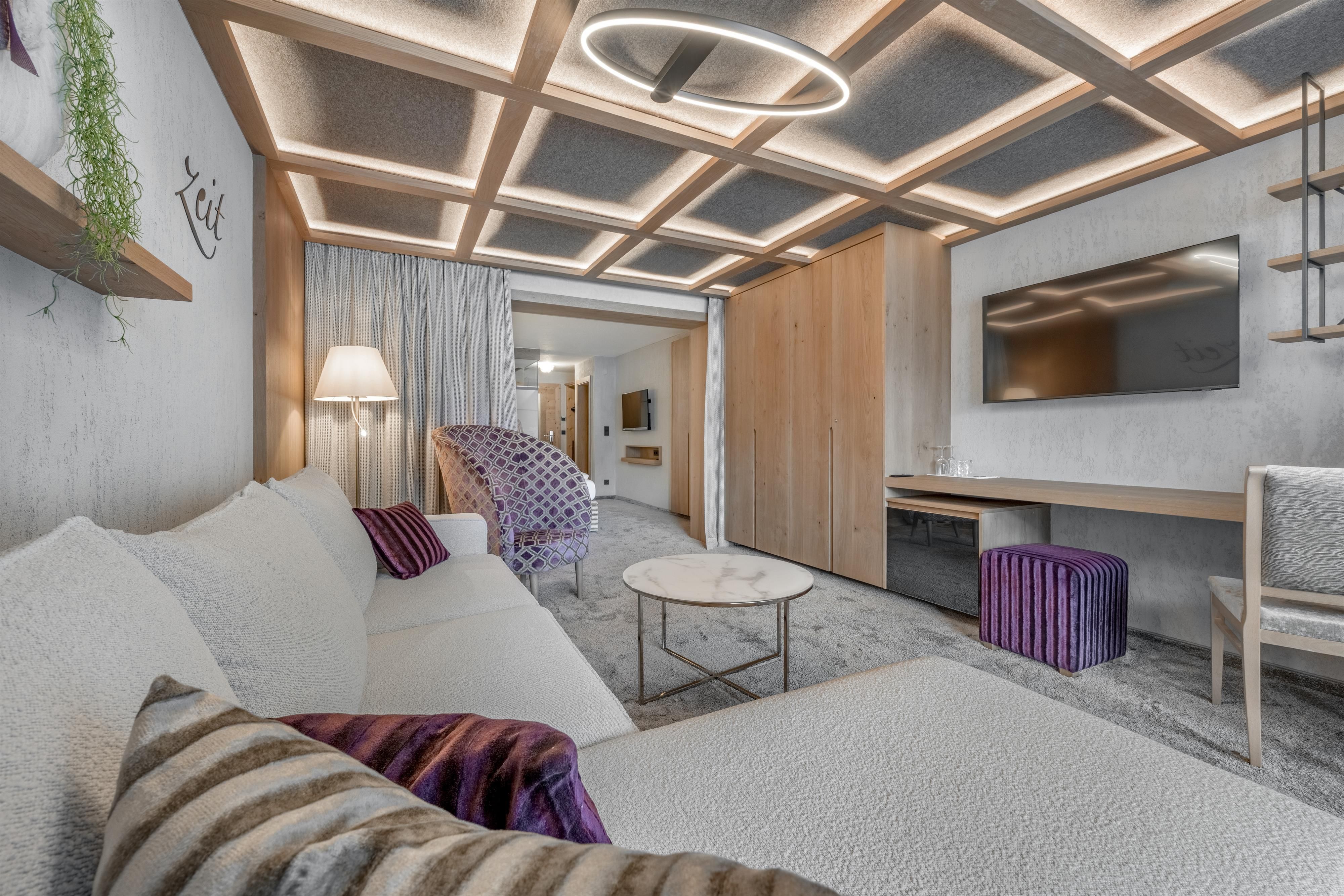 Ein modernes Wohnambiente mit einem weißen Sofa, einem Couchtisch und einem großen Fernseher. Die Sanierung bietet warmes Licht und eine gemütliche Atmosphäre.