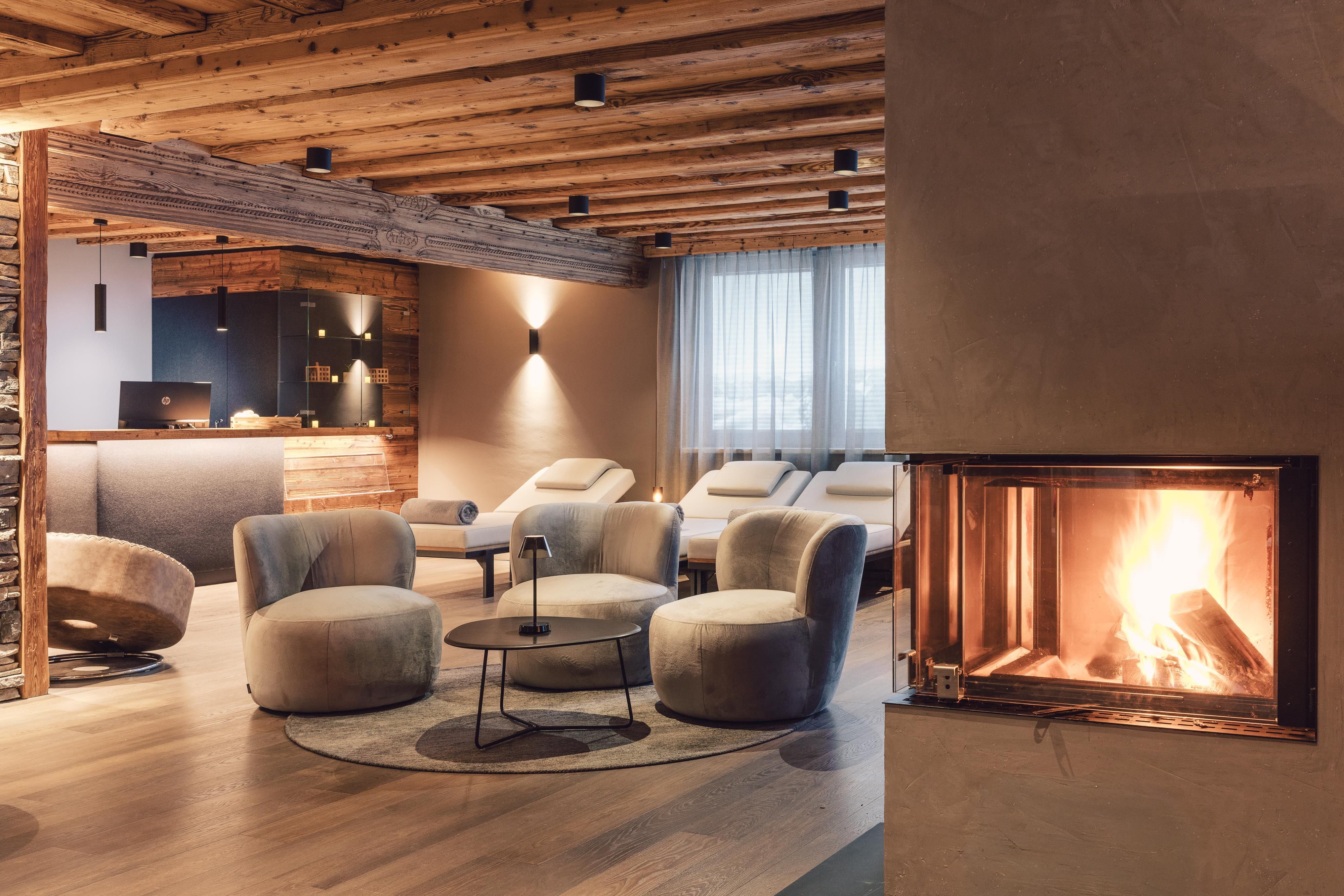 Ein modernes Wohnzimmer mit gemütlichen Sesseln und einem offenen Kamin. Helle Farben und Holzakzente sorgen für eine angenehme Atmosphäre.