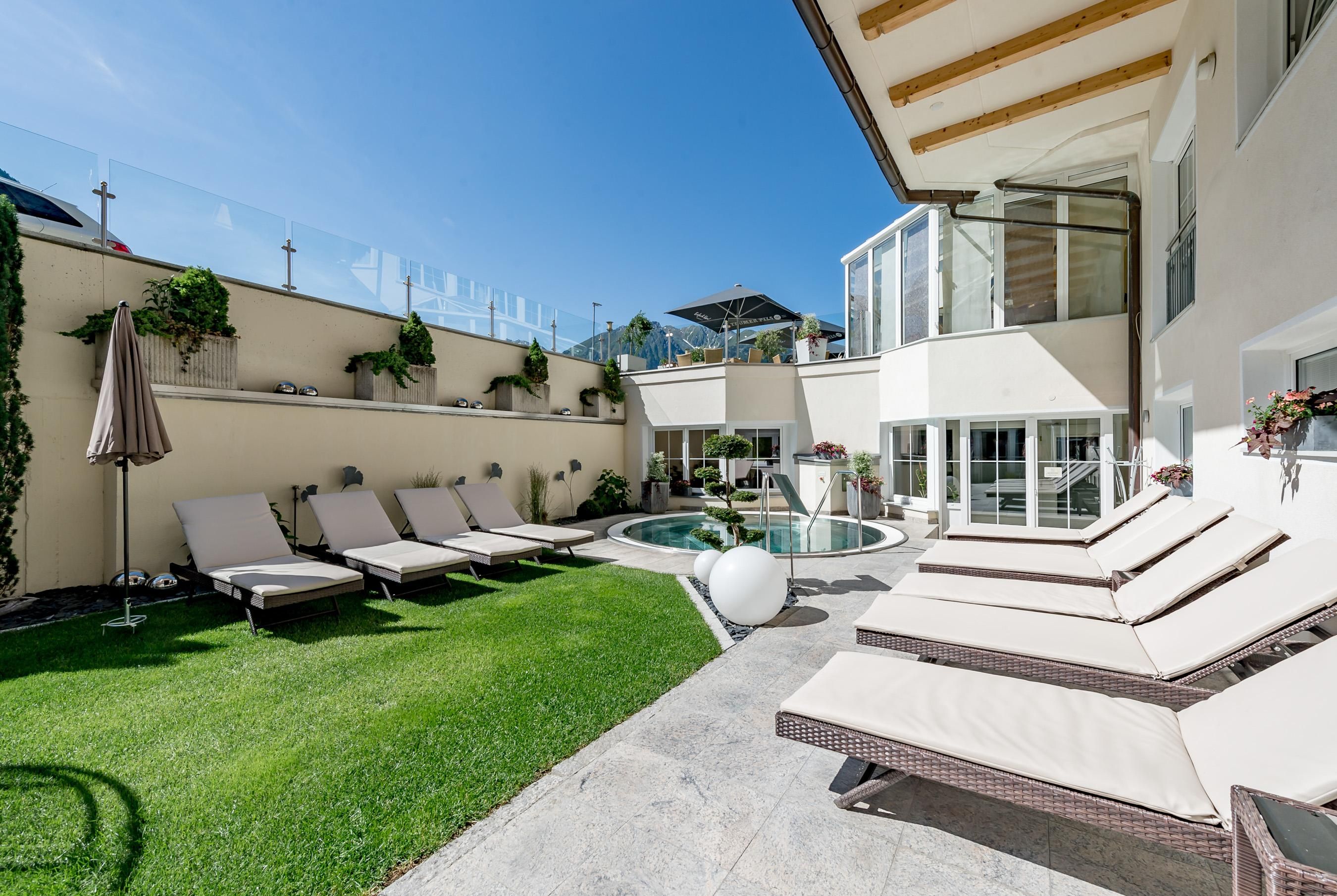 Ein moderner Garten mit Liegen und einem kleinen Pool. Die Umgebung ist hell und einladend, ideal zum Entspannen.