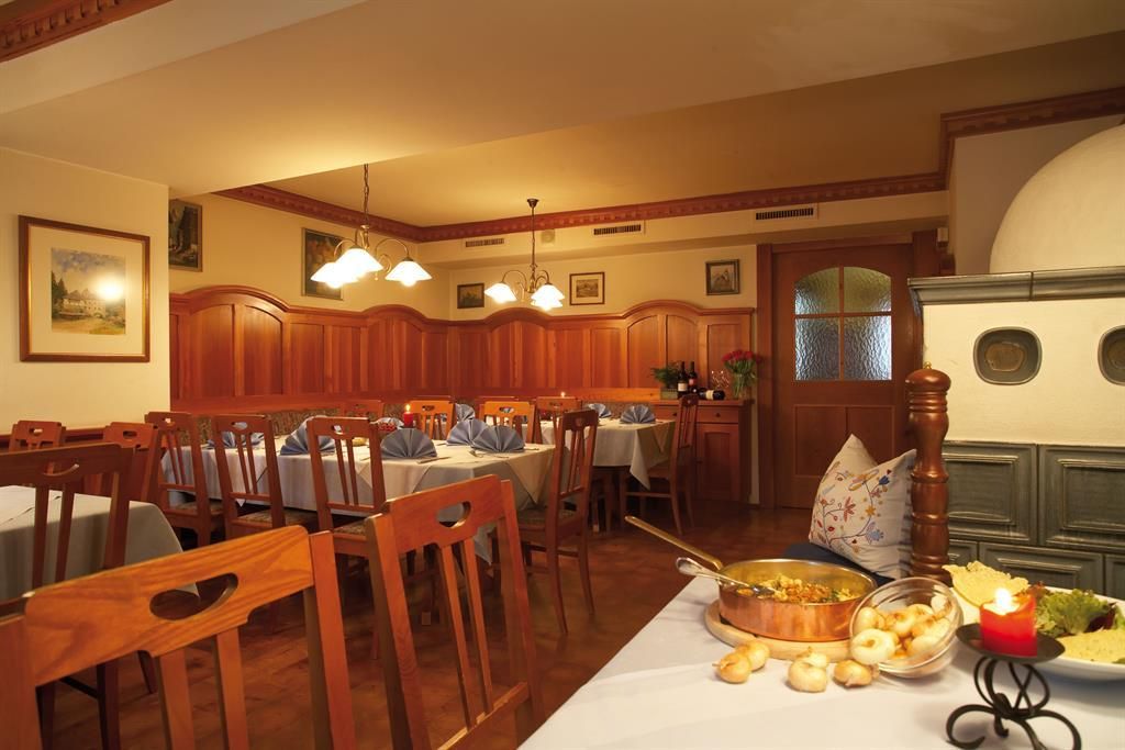 Ein gemütliches Restaurant mit Holzmöbeln und runden Tischen. Auf den Tischen sind Teller und eine Speise zum Servieren platziert.
