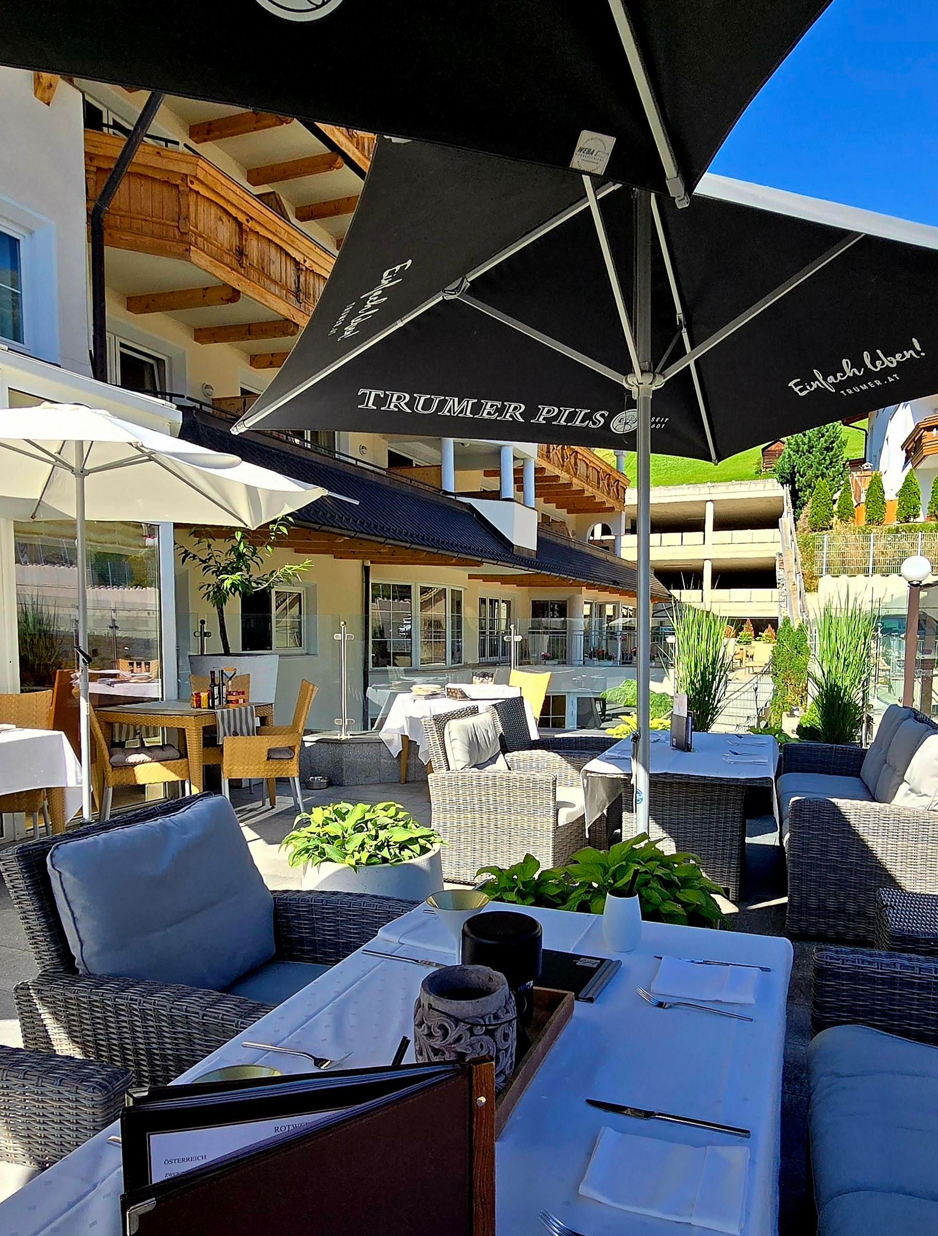 Ein gemütliches Restaurant mit modernen Möbeln im Freien. Sonnenschirme bieten Schatten für die Gäste.