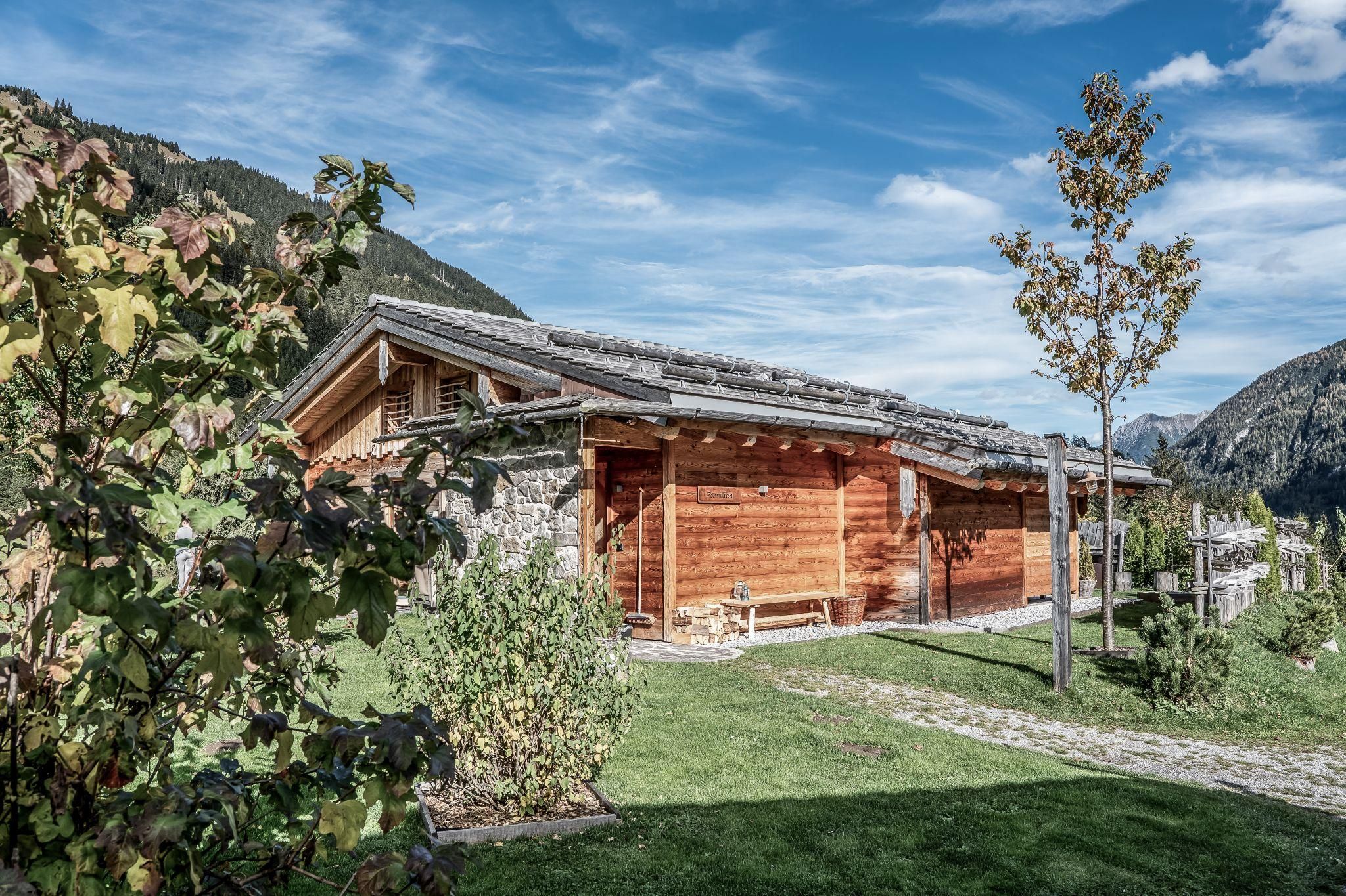Ein charmantes Chalet in einer malerischen bergigen Umgebung. Es ist umgeben von Bäumen und einem grünen Garten.