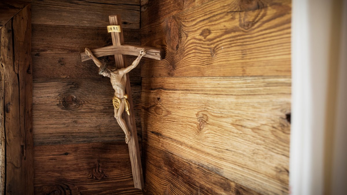 Wie in vielen Tiroler Bauernhäusern und Hütten hängt auch im Chalet Friedlach ein Kruzifix im sogenannten Herrgottswinkl hinter dem Tisch., © Tirol Werbung/Lisa Hörterer