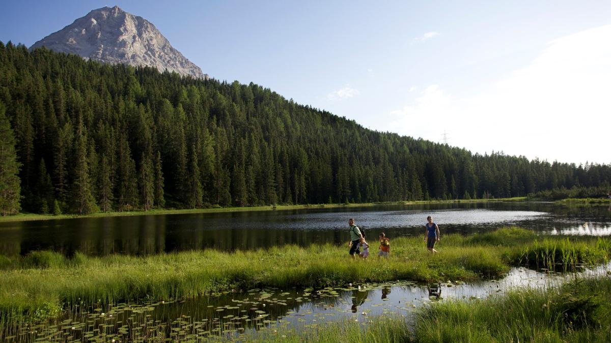 Der Schwarze See heißt nicht umsonst so – das Hochmoor, in dem das Naturdenkmal oberhalb von Nauders liegt, färbt das Wasser dunkel. Im Sommer aber schmückt sich der See mit unzähligen weißen Seerosen., © Nauders