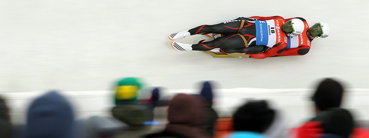 Raketenschnell rasen die Rennrodel an den Zuschauern im Olympia-Eiskanal in Innsbruck-Igls vorbei, © Michael Kristen / kristen-images.com