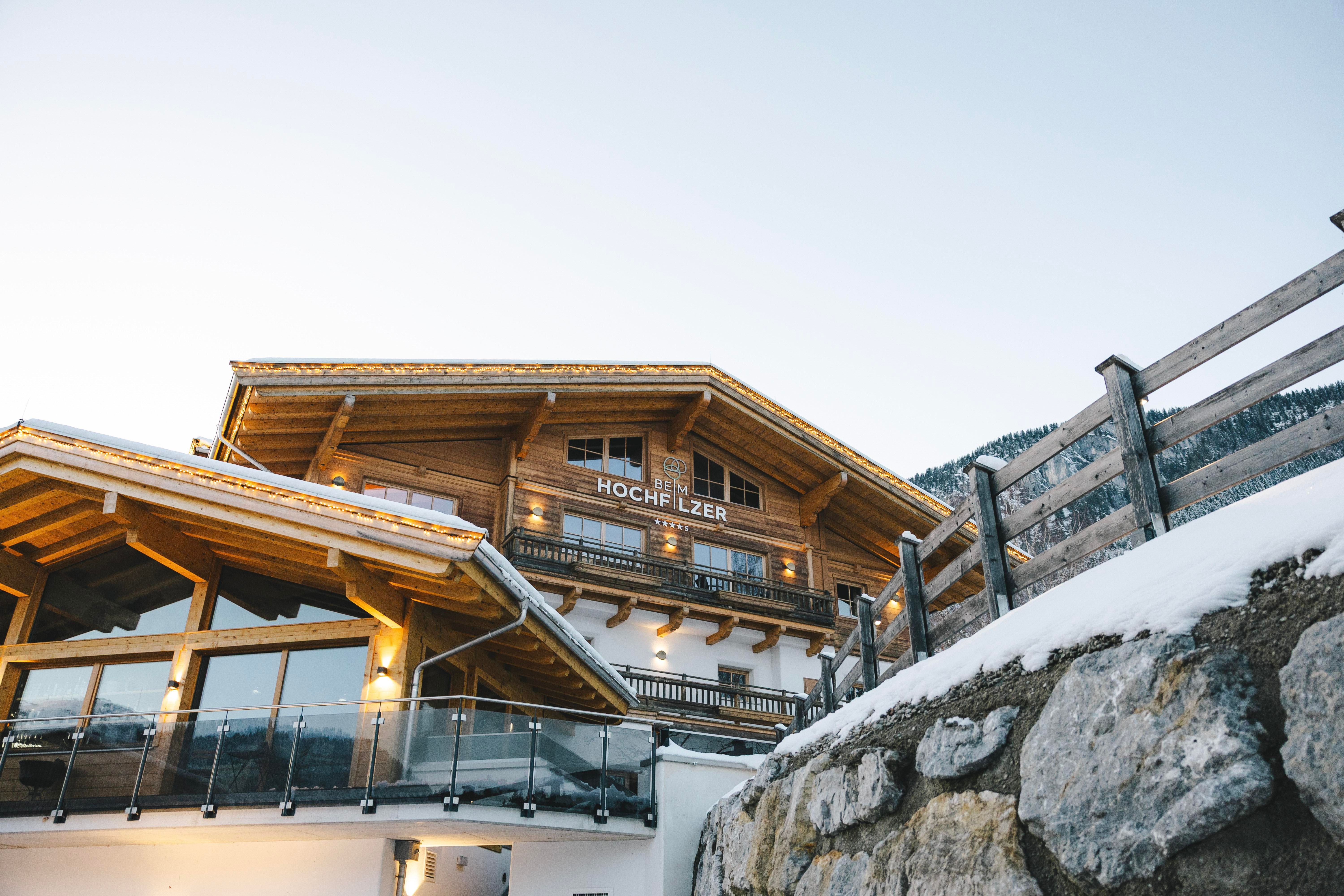 Ein gemütliches Berghaus aus Holz mit einem Balkon und einer schönen Aussicht. Die Umgebung ist von Schnee und Bergen geprägt.