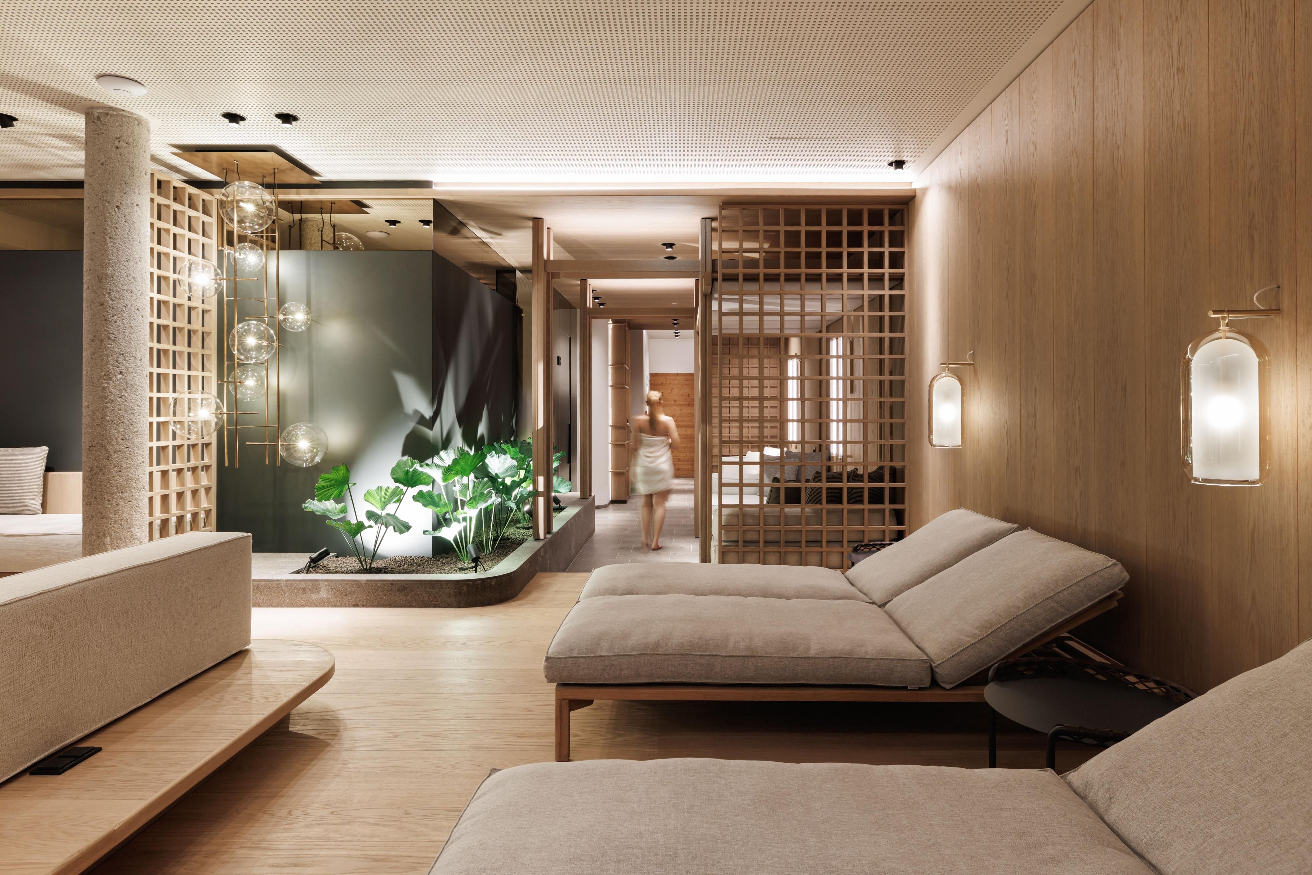 Ein eleganter Wellnessbereich mit modernen Liegen und warmen Holztönen. Pflanzen und sanfte Beleuchtung schaffen eine entspannende Atmosphäre.