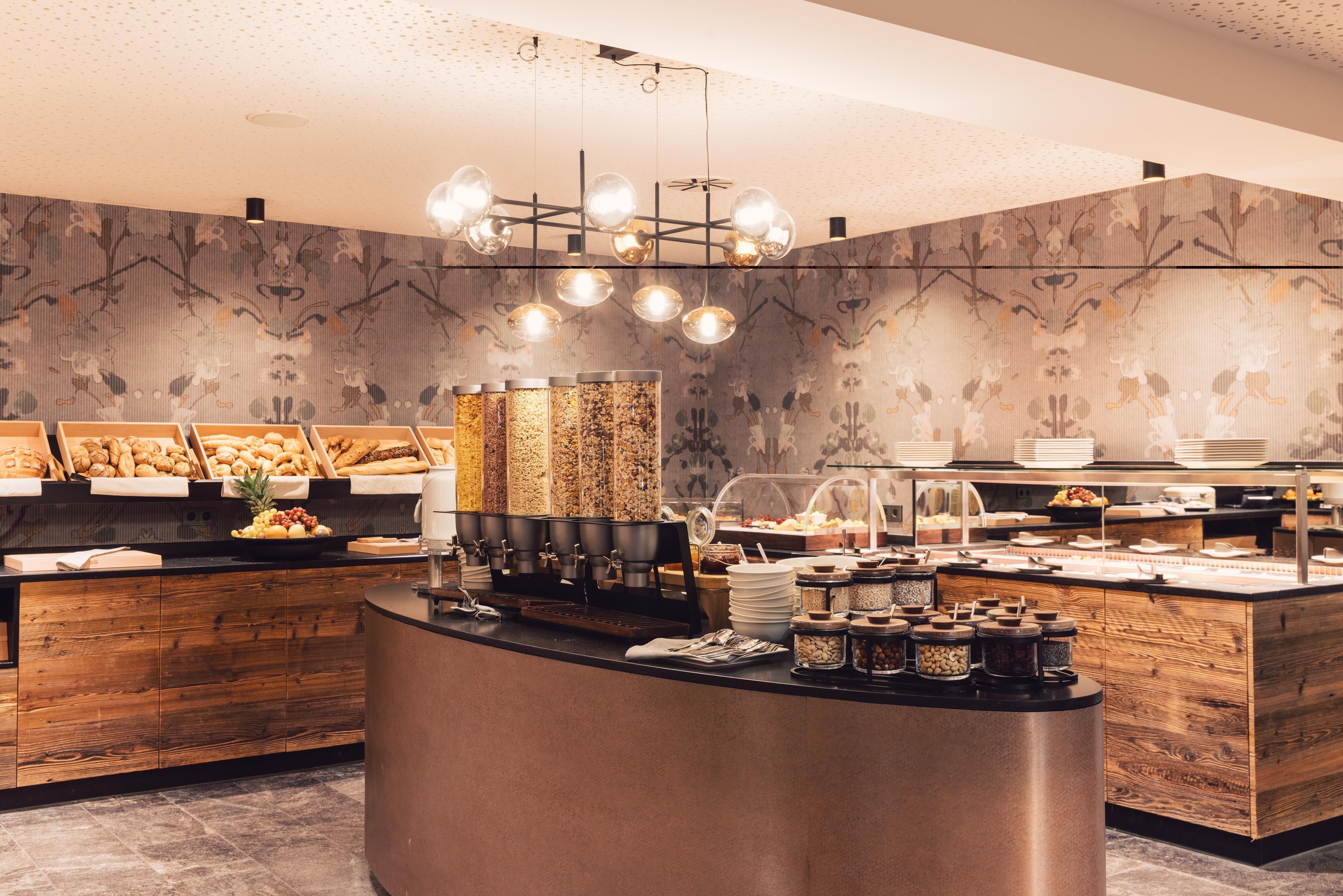 Ein einladendes Frühstücksbuffet mit verschiedenen Brötchen, Cerealien und Marmeladen. Die warme Holzdekorierung schafft eine gemütliche Atmosphäre.