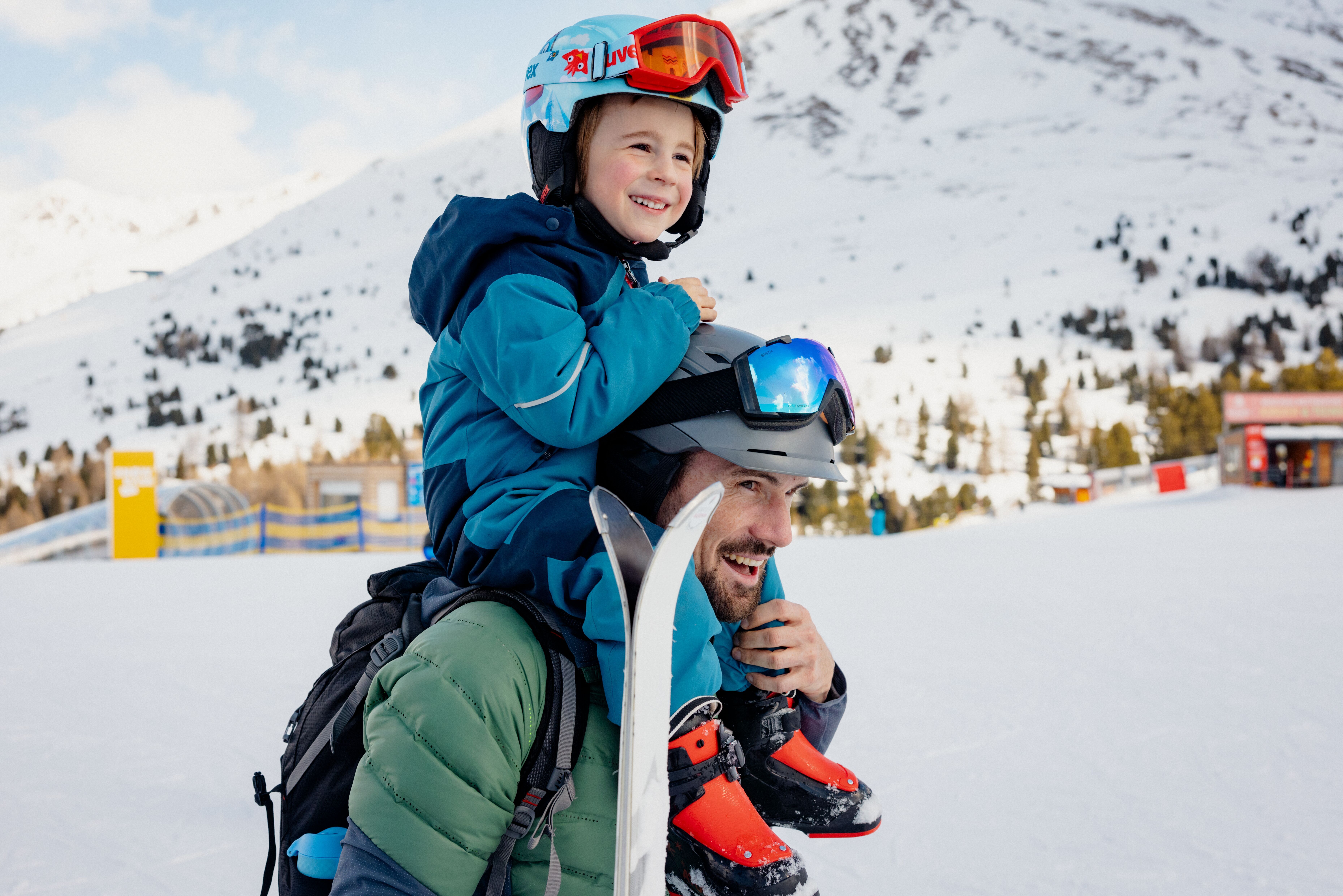 Vater trägt Sohn auf seinen Schultern. Sie sind am Weg zum Skifahren