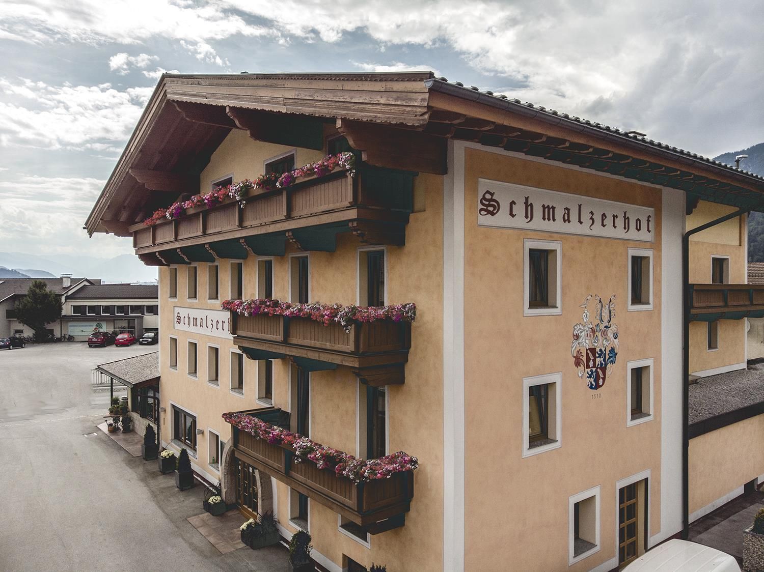 Ein charmantes Hotel mit balcons und Blumen, umgeben von einer malerischen Landschaft. Die Fassade ist in sanften Farben gehalten und bietet eine einladende Atmosphäre.