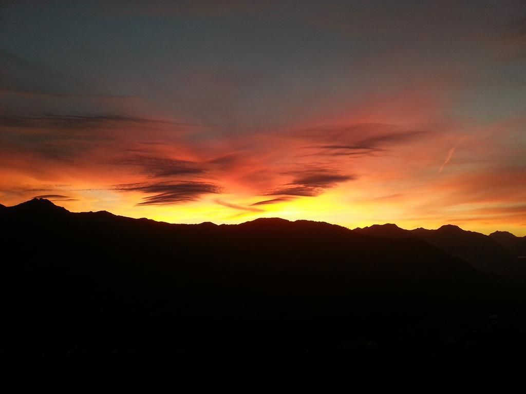 Ein atemberaubender Sonnenuntergang über den Bergen. Der Himmel leuchtet in leuchtenden Orange- und Rottönen.